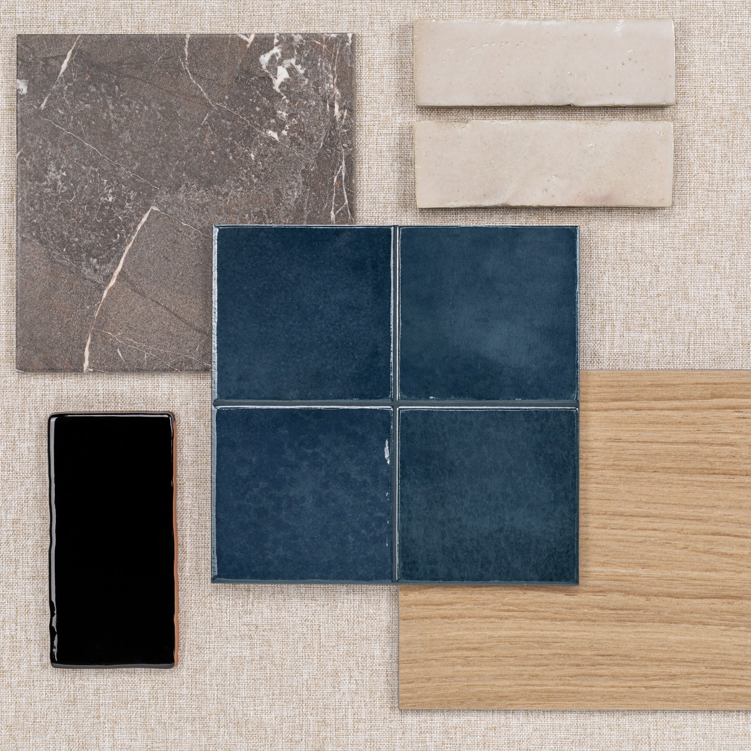 Assortment of ceramic and porcelain tiles with wood and stone textures arranged on fabric background
