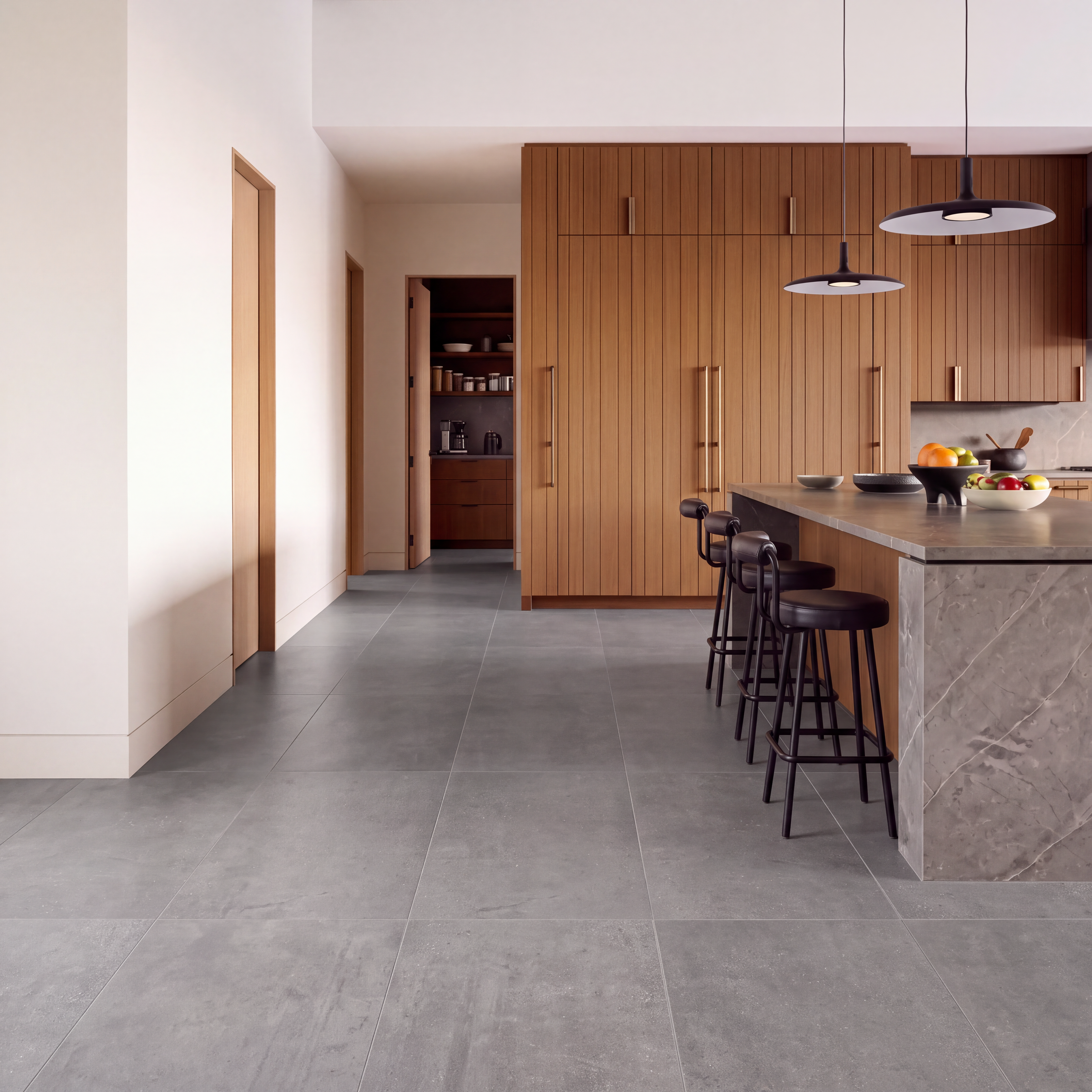 Modern kitchen with large gray floor tiles, wood cabinetry, stone island, bar stools, and pendant lights