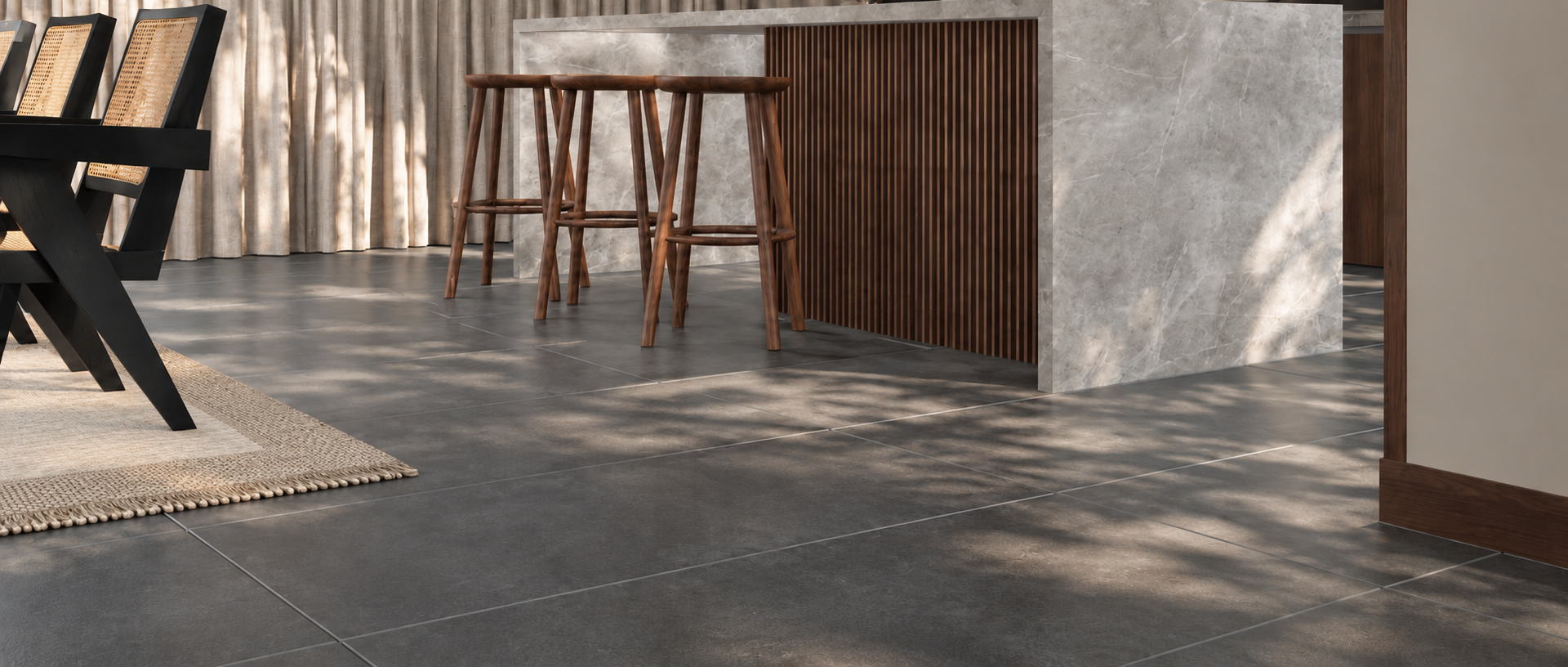 Modern interior with large gray format floor tiles wood bar stools and a slatted cabinet bathed in sunlight