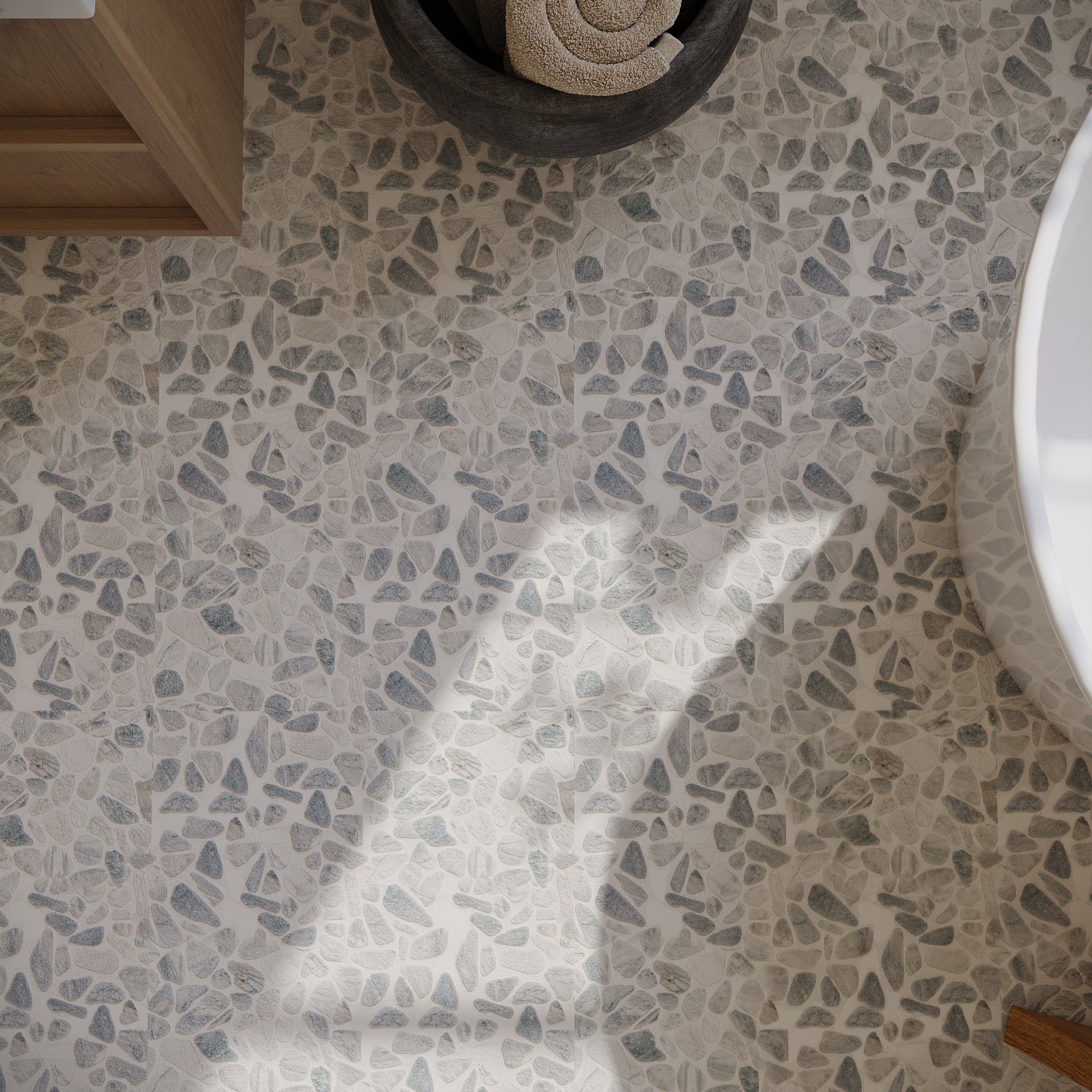 Light gray and cream terrazzo flooring with irregular stone fragments in a modern bathroom setting with natural light.