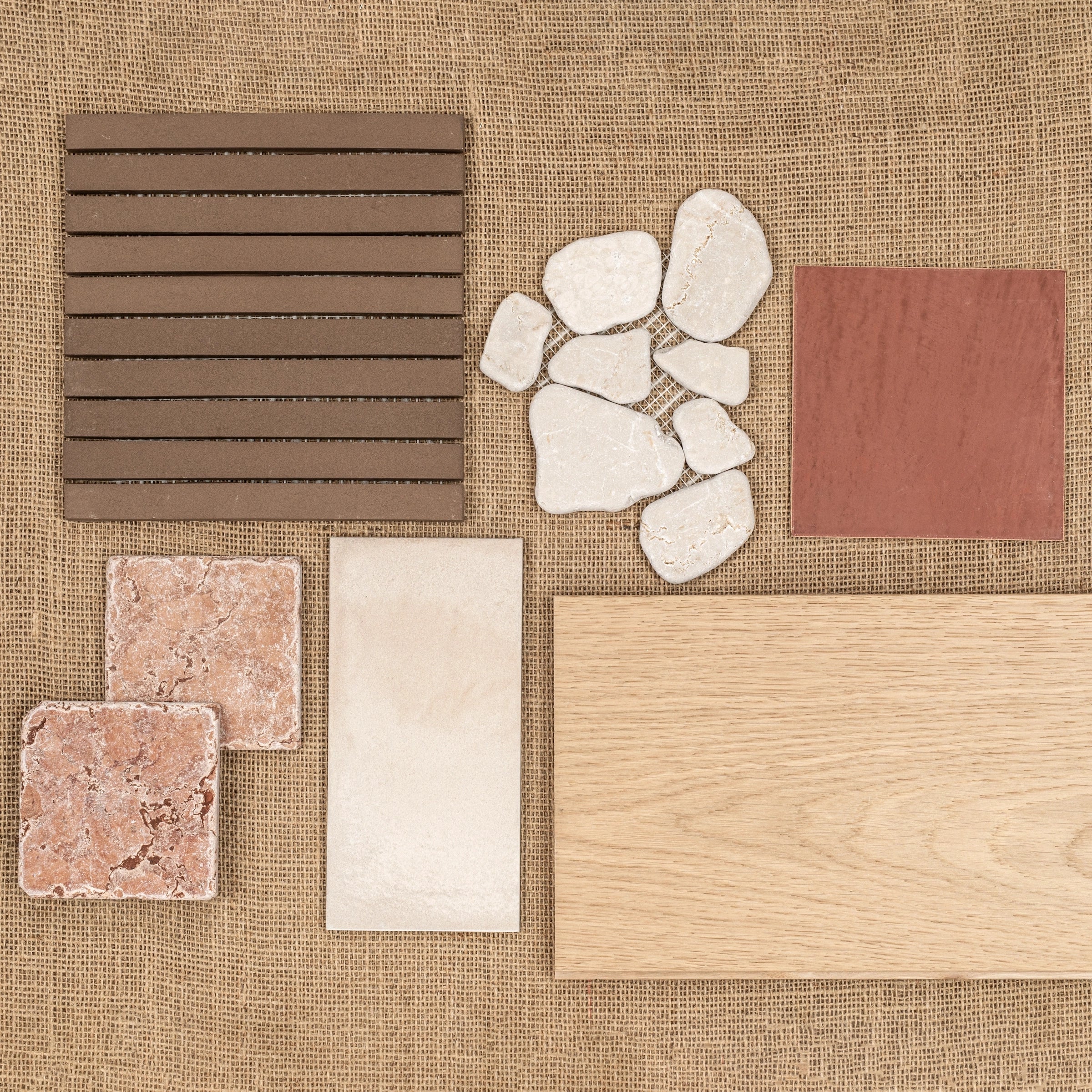 Various tile and wood flooring samples arranged on burlap fabric background for design inspiration