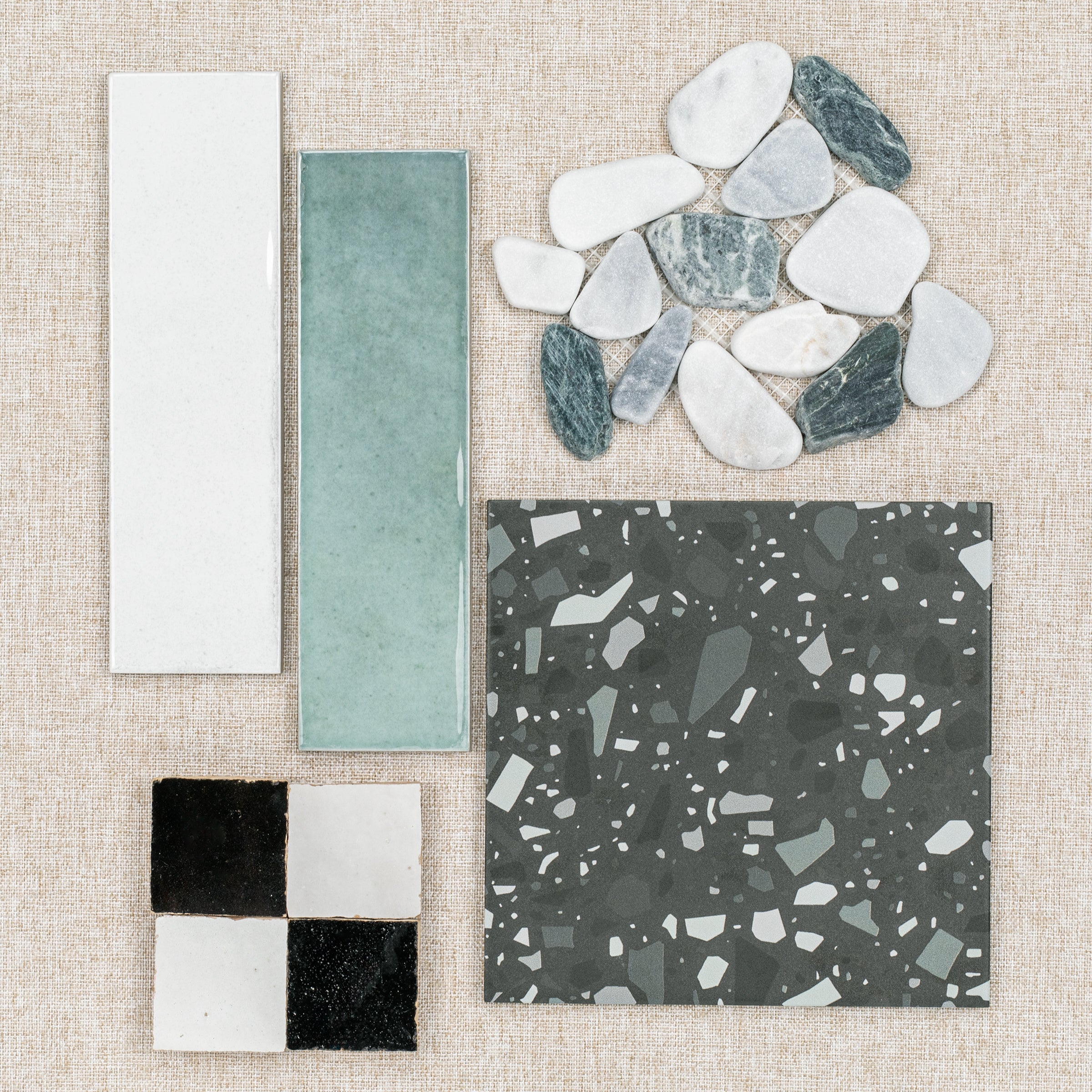 Assortment of ceramic and porcelain tiles with natural stone pieces arranged on fabric background