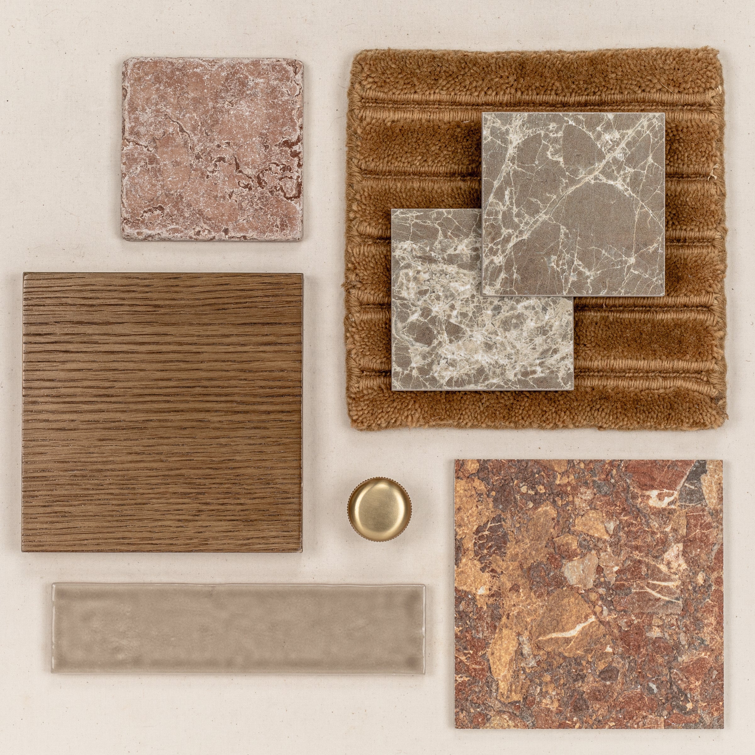 Assortment of textured tiles and wood samples in warm earthy tones arranged with a brass accent on neutral background
