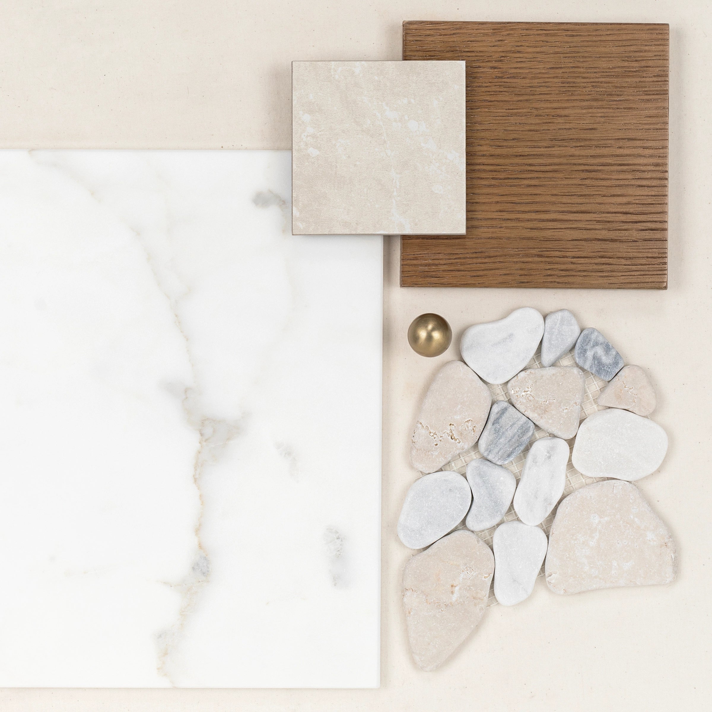 Flat lay of natural stone tile samples, wood texture, smooth beige tile, and mixed stone pebbles on a neutral surface