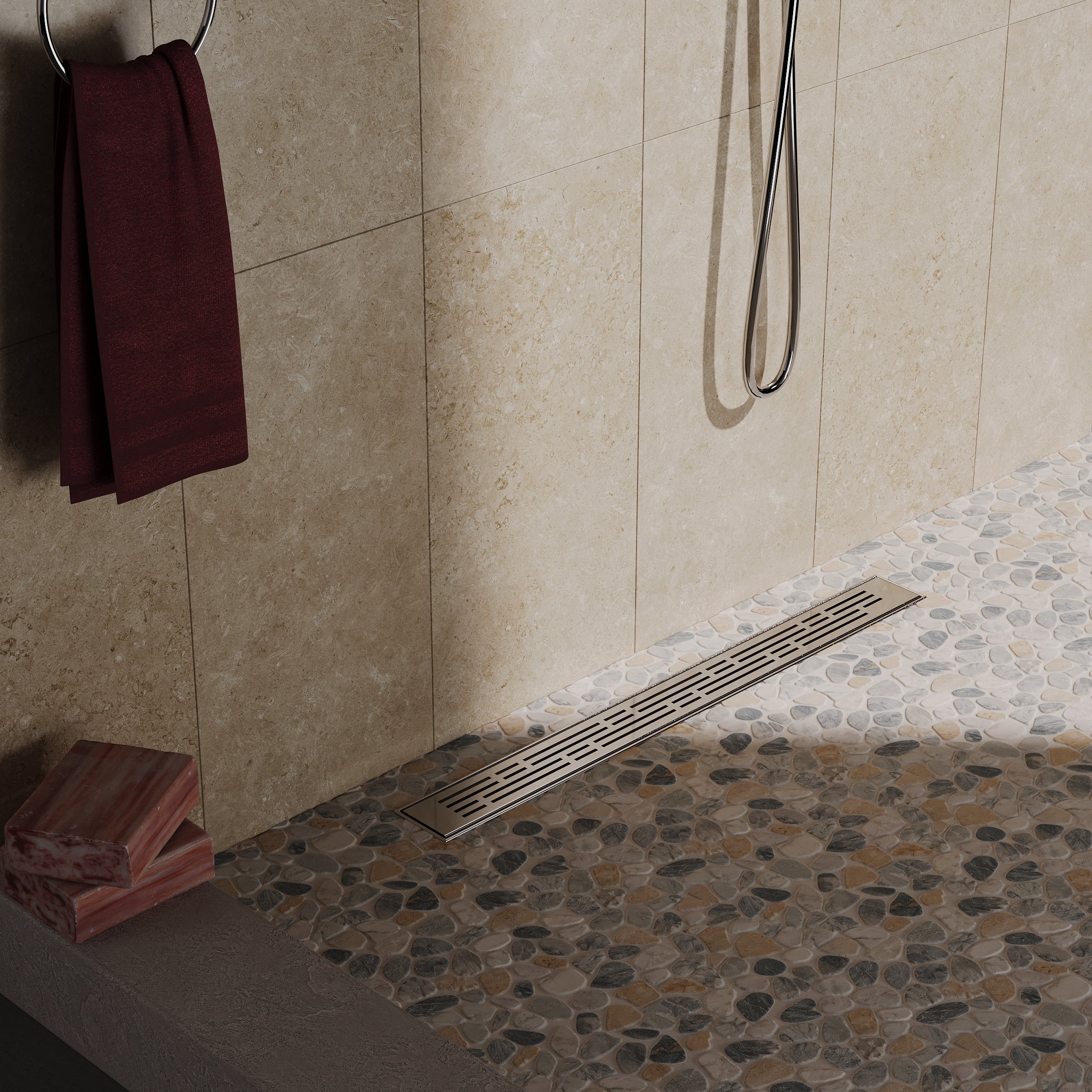 Stone pebble mosaic flooring with beige large wall tiles, silver linear drain, and maroon towel in modern shower space