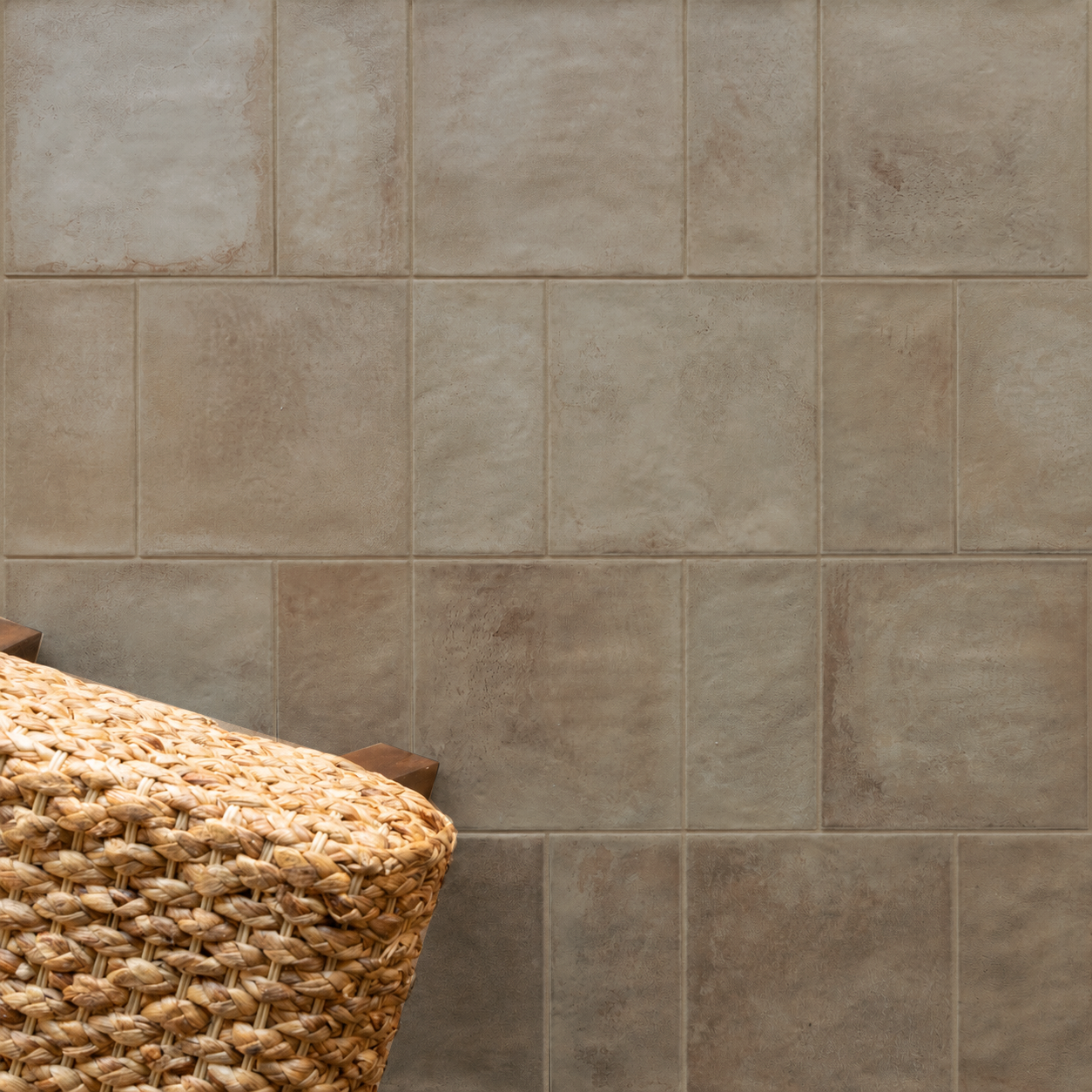Neutral square tiled wall with a woven basket in warm sunlight