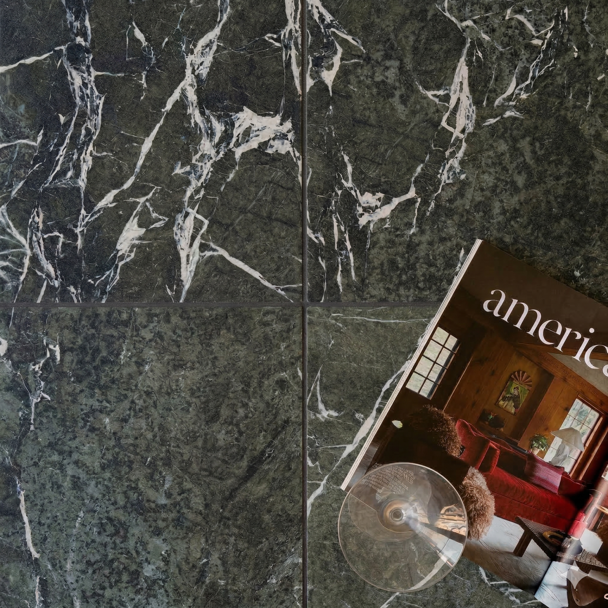Dark green ceramic tiles with white marble-like veining arranged in a grid with a lifestyle magazine nearby