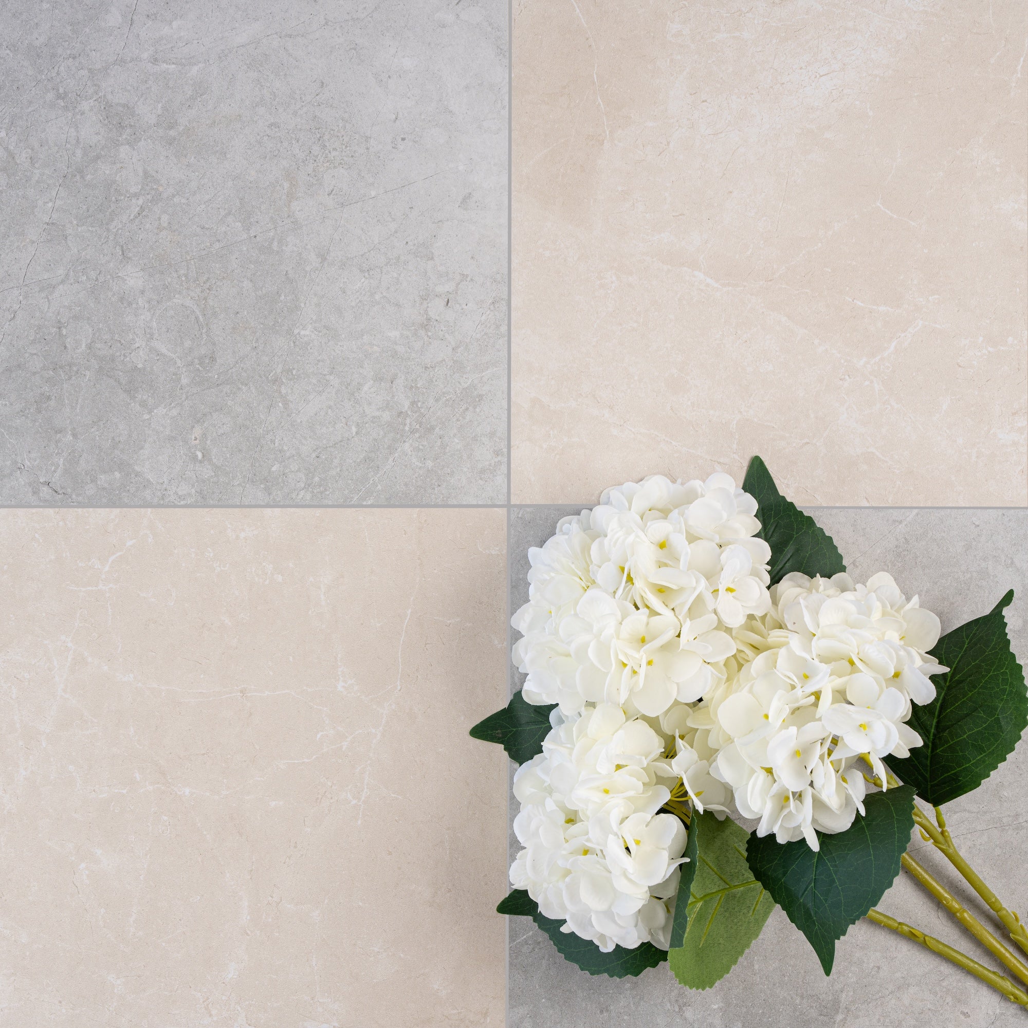 Four large ceramic tiles in soft gray and beige tones arranged in a square with white hydrangea flowers on top