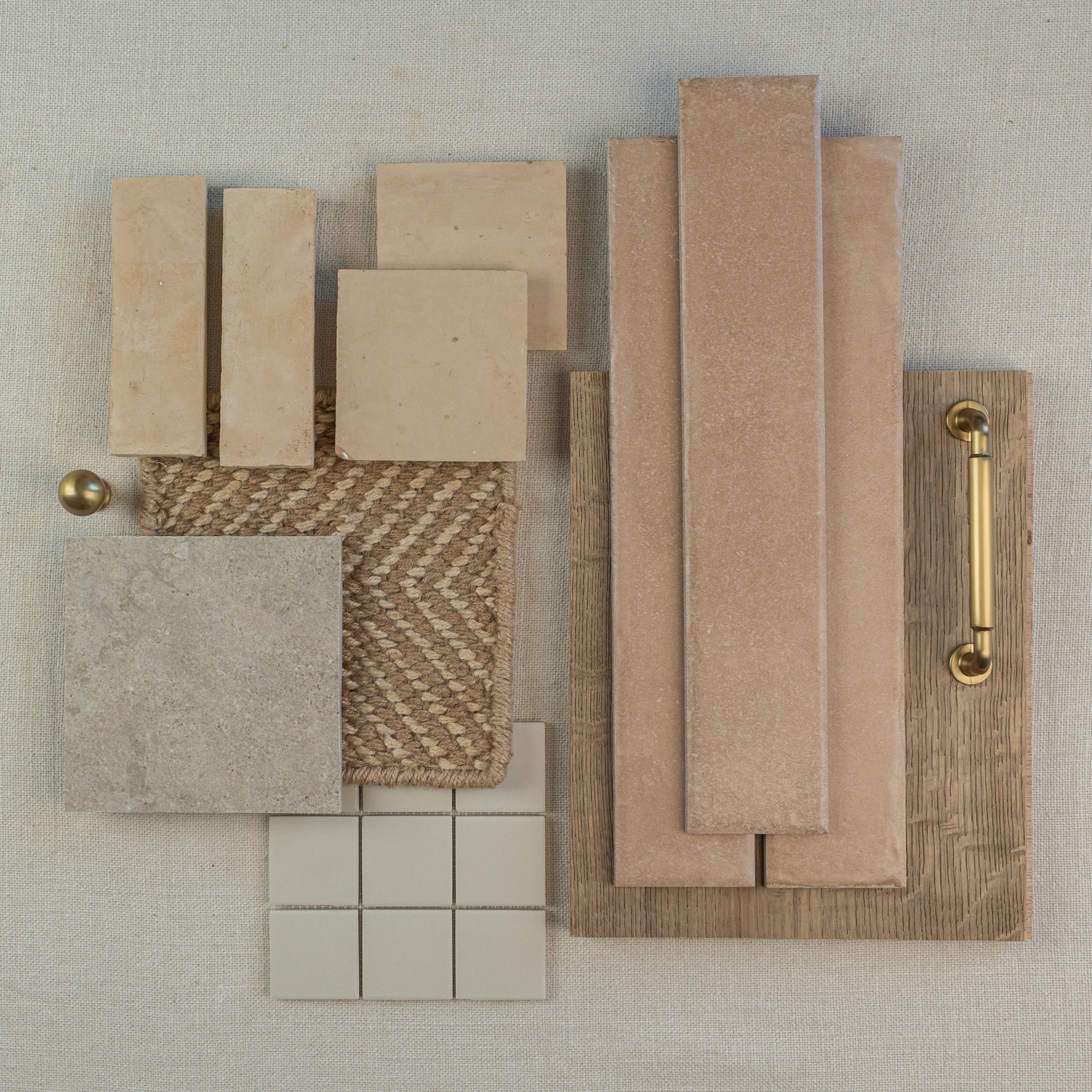 Overhead view of beige and terracotta ceramic tiles, textured fabric swatches, wood sample with brass handle on neutral background