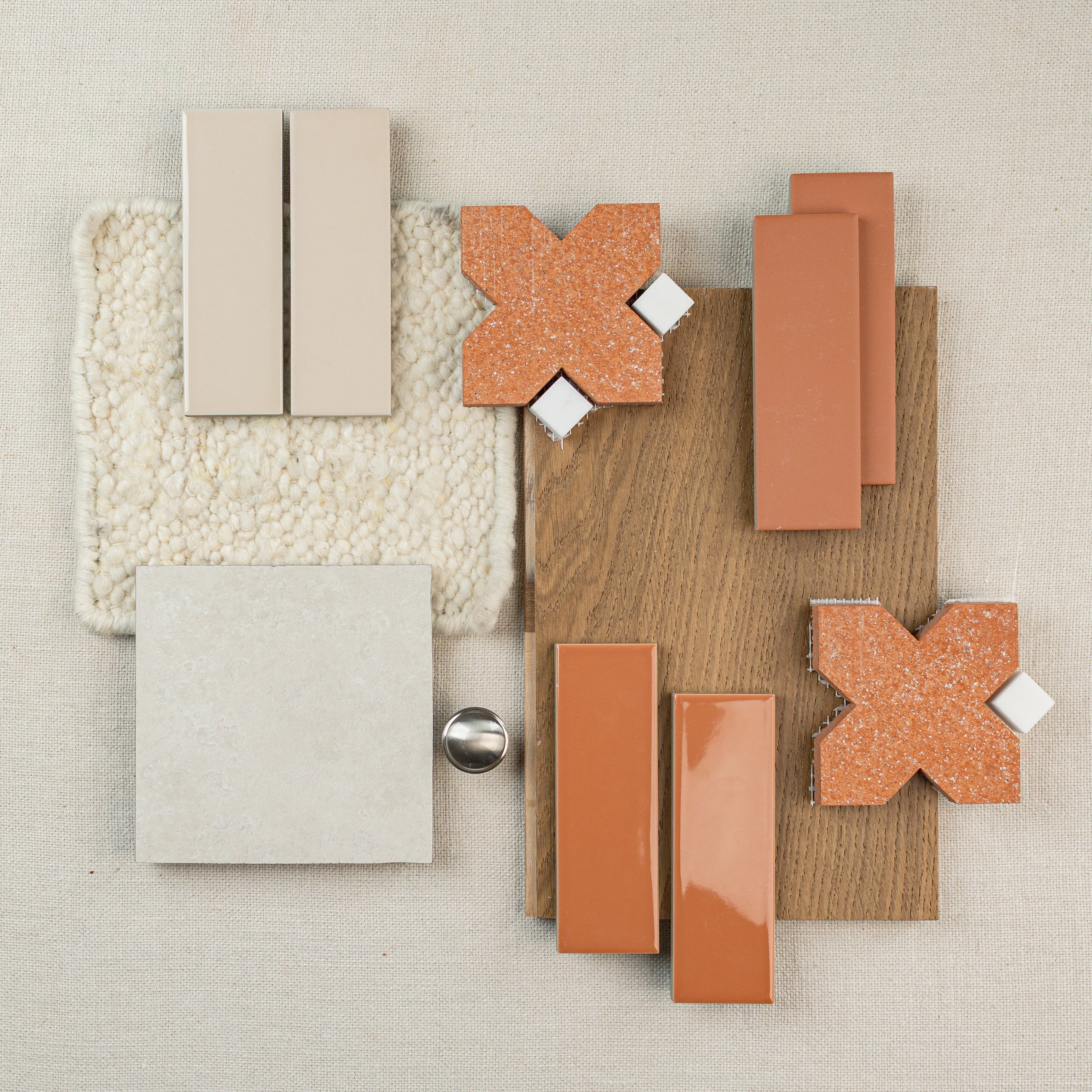 Flat lay of tile samples, terracotta X-shaped tiles, ceramic tiles, wood flooring, and textured cream carpet swatch