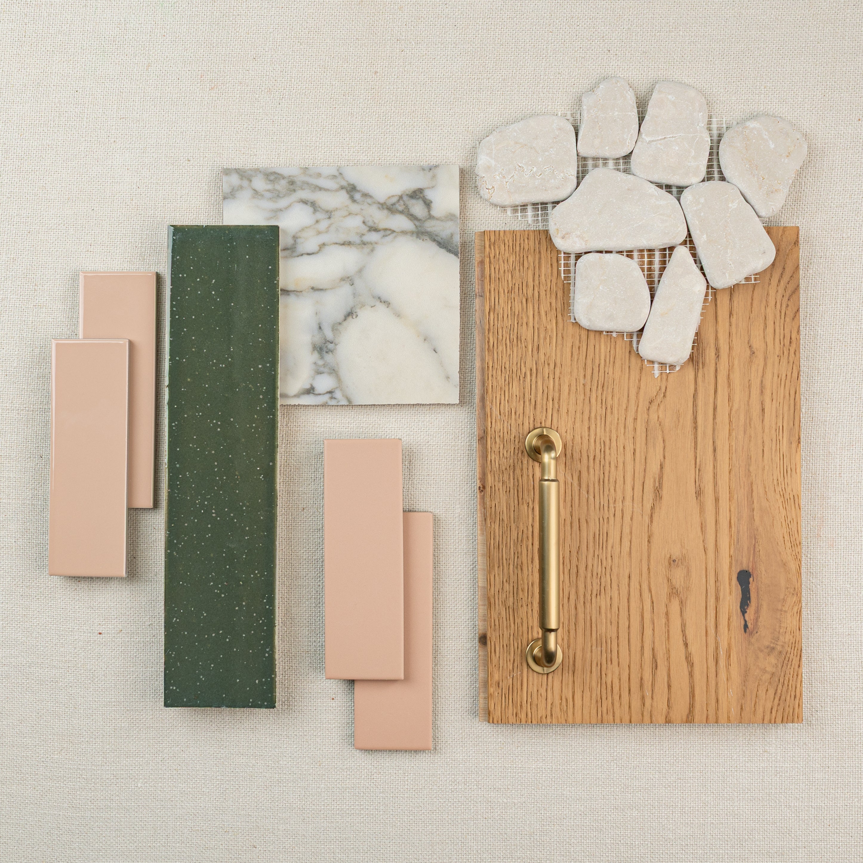 Tile and wood flooring samples with brass handle and natural stone pieces arranged on fabric background
