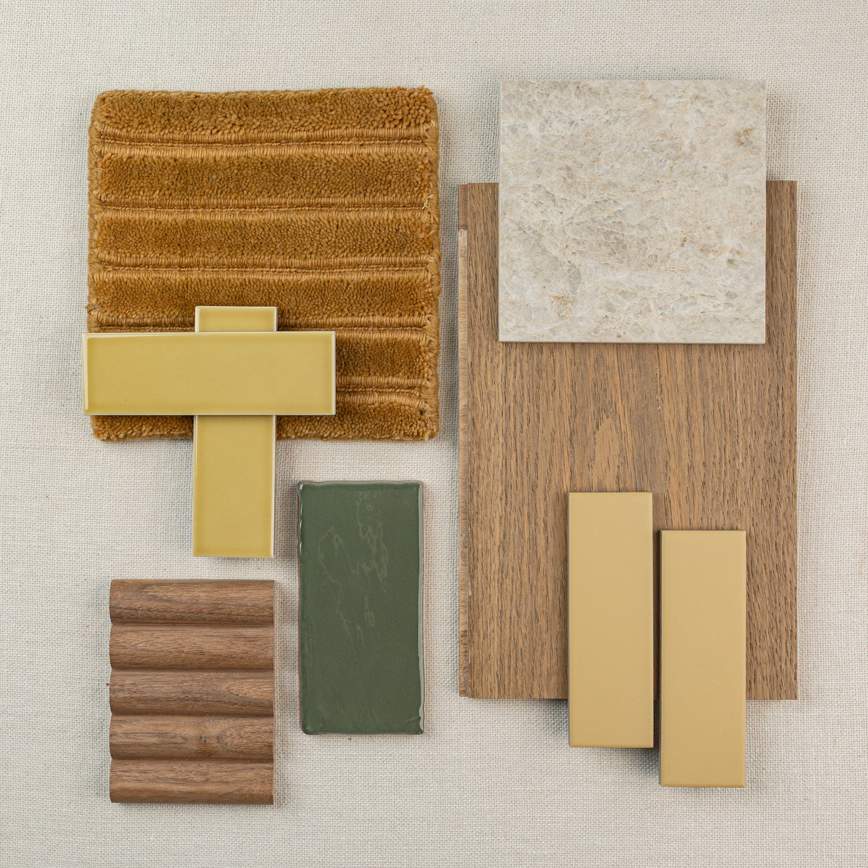 Assortment of design materials including wood samples, tiles, fabric swatch, and muted yellow handles on a neutral background