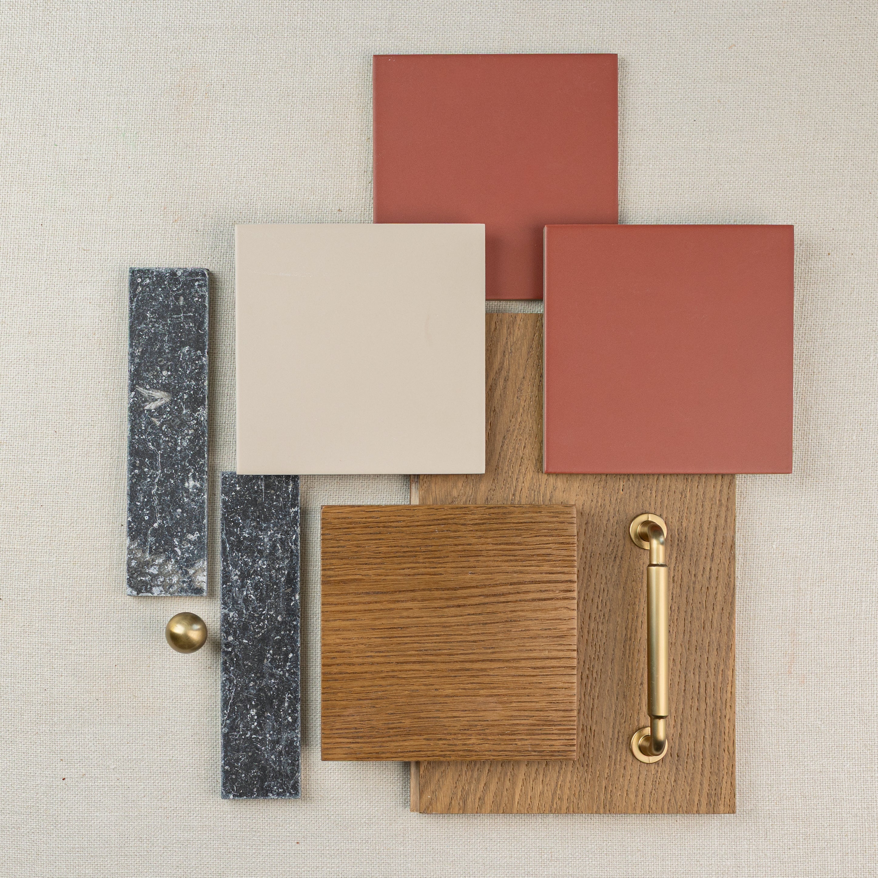 Layout of terracotta and beige ceramic tiles with oak wood flooring and brass hardware pieces on fabric