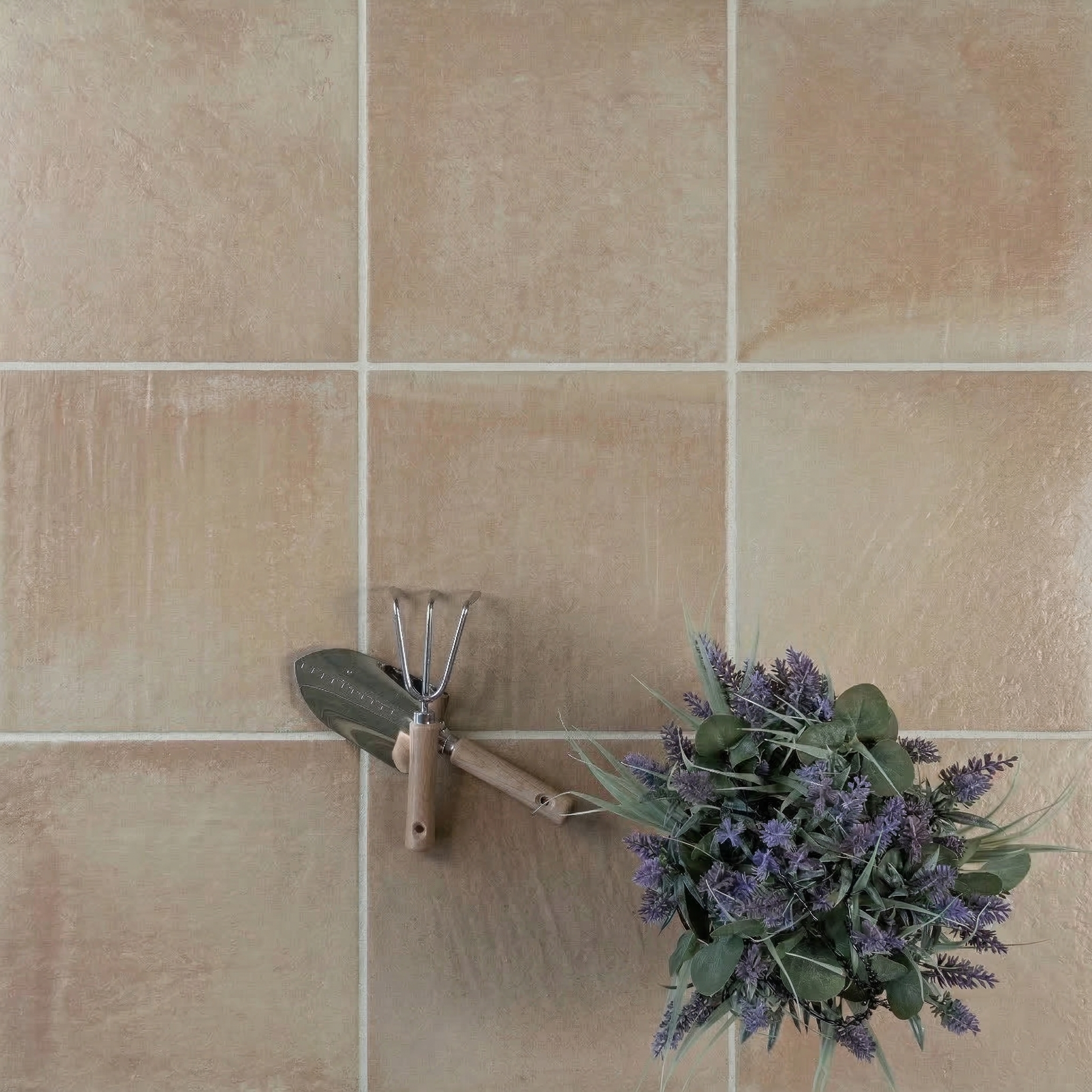 Soft beige ceramic tiles with subtle texture arranged in a grid alongside garden tools and a bouquet of lavender