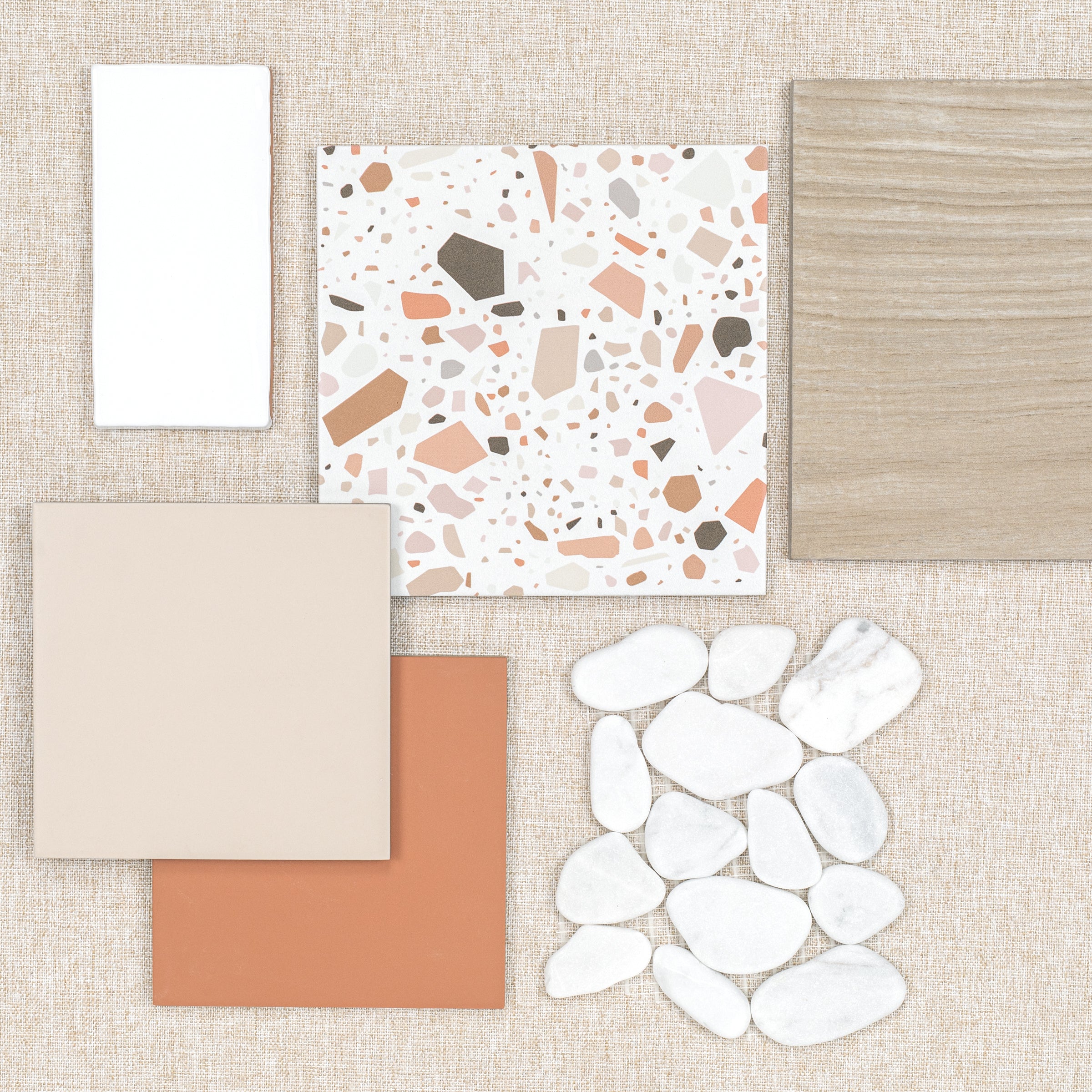 Flat lay of assorted tiles and white pebble stones on a textured beige background surface