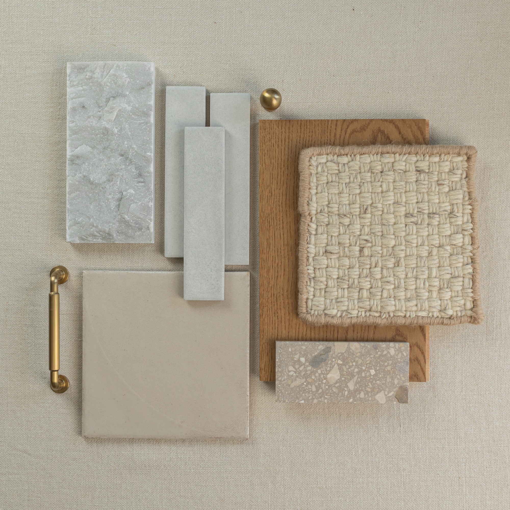 Flat lay of neutral beige fabric with wood, woven textile, ceramic tile, terrazzo, matte stone and brass hardware samples