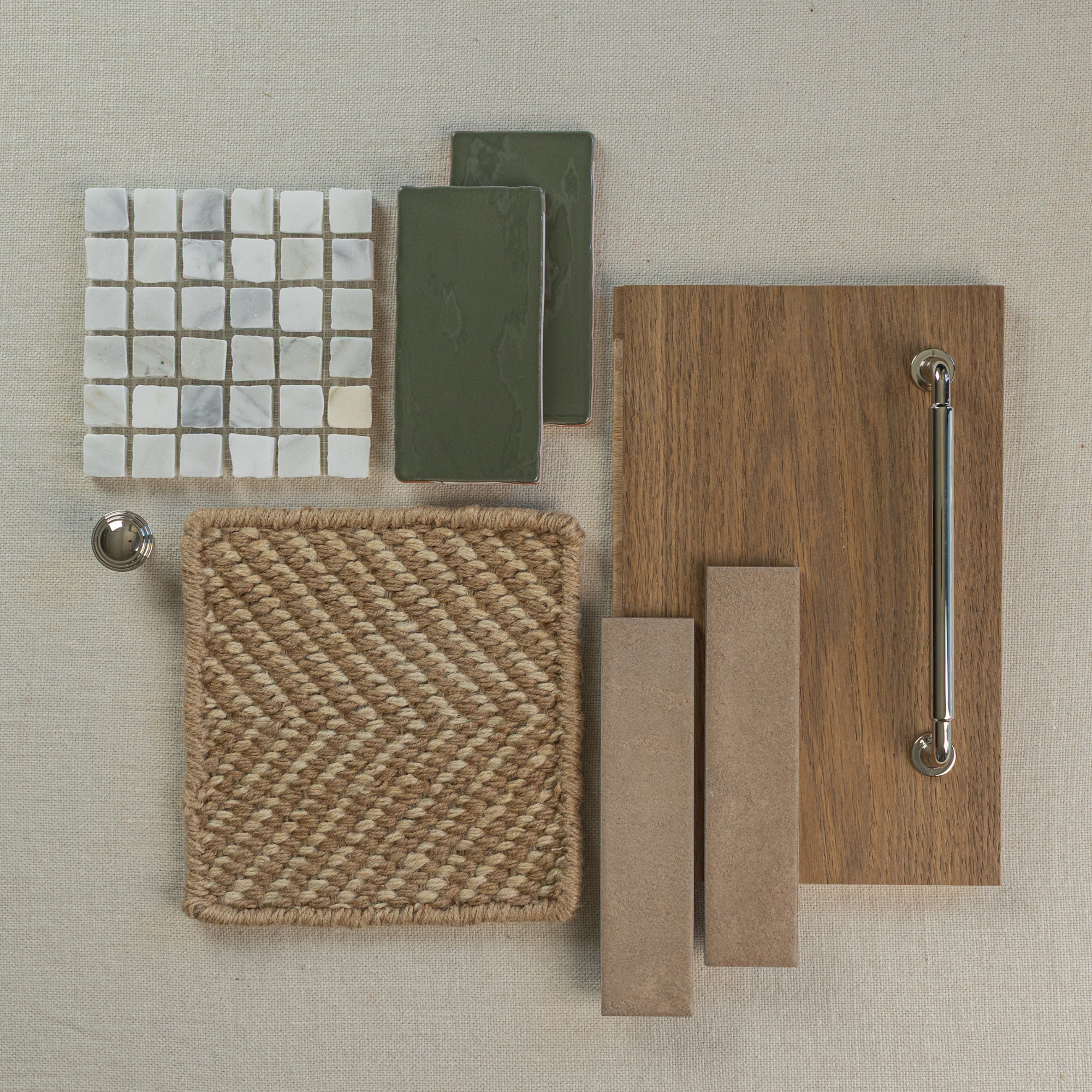 Flat lay of natural woven fabric sample, green ceramic tiles, marble mosaic tiles, wood plank with chrome handle, and two beige rectangular tiles on linen background