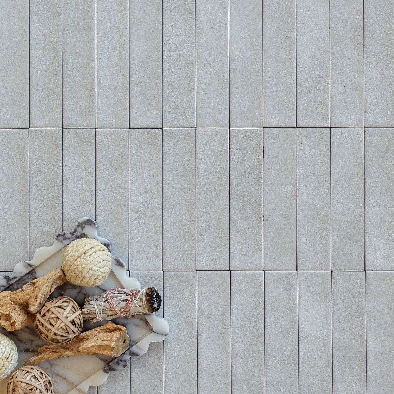 Gray rectangular ceramic tiles laid in a staggered pattern with decorative natural wicker and wood accents on marble nearby