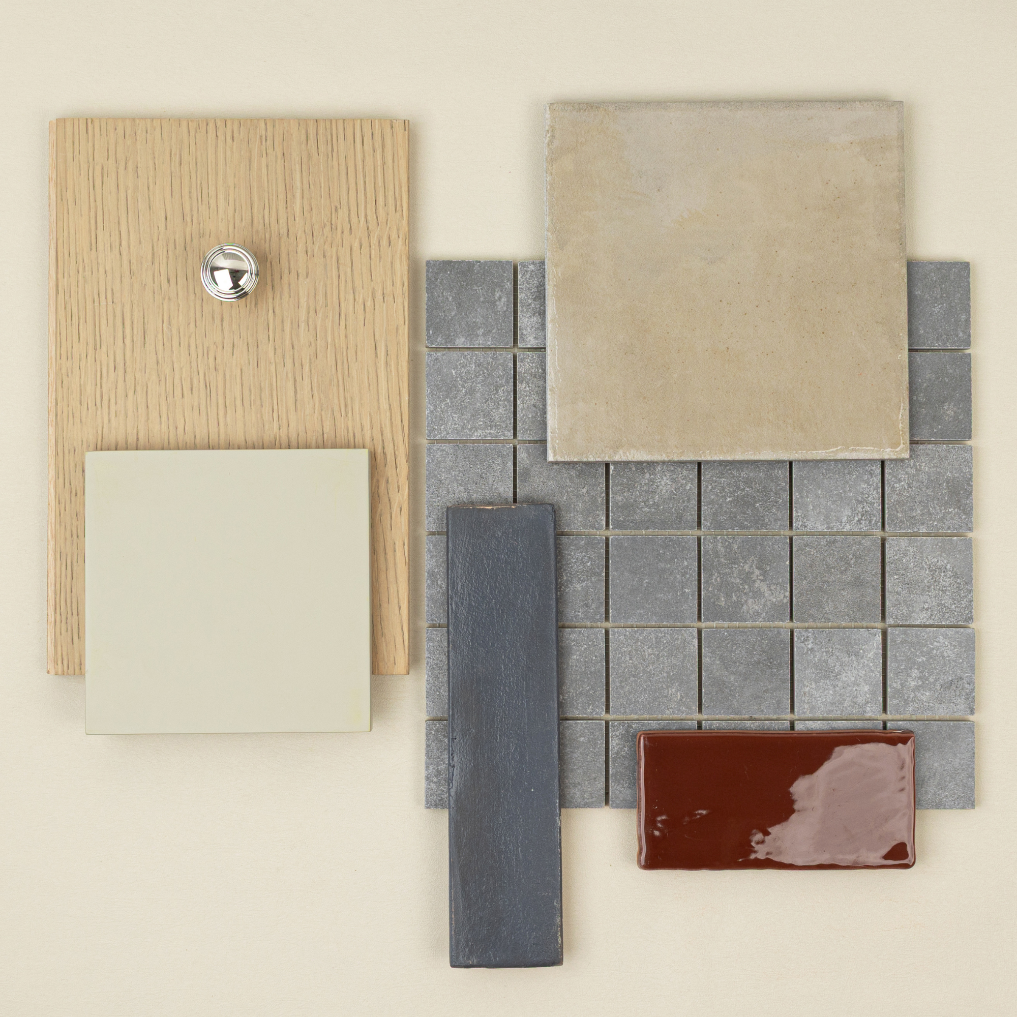 Flat lay of neutral wood sample, matte beige tile, small grey square mosaic, dark blue and glossy reddish-brown ceramic tiles on cream background