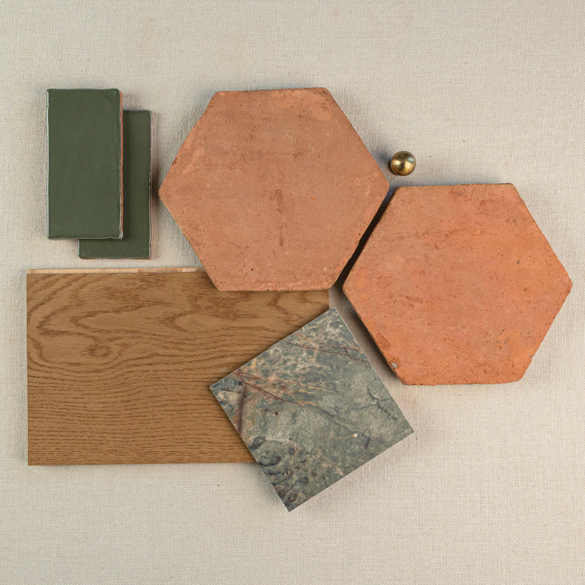 Hexagonal terracotta tiles paired with green ceramic rectangles, wood grain plank, and mottled stone square on beige fabric