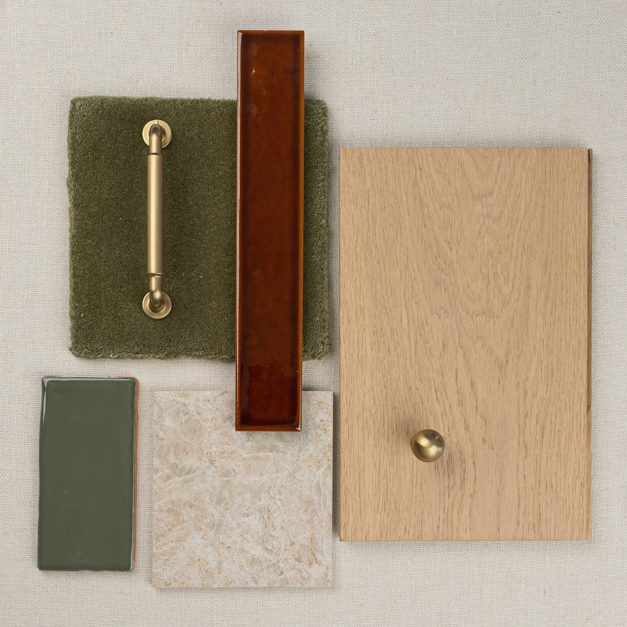 Flat lay of oak wood sample, olive green fabric, brass handle and knob, rust-colored tile, green and beige ceramic tiles on neutral background