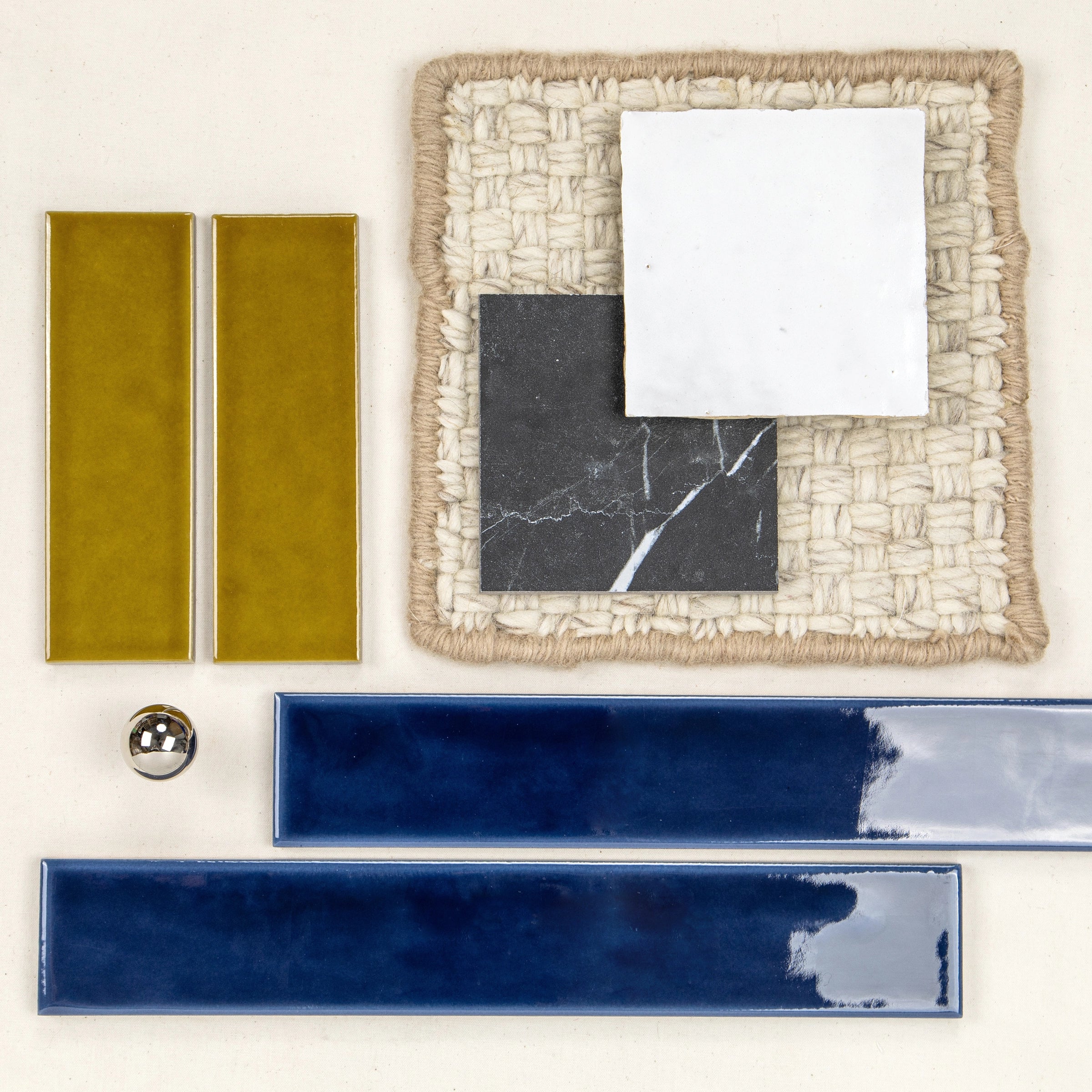 Glossy golden rectangular tiles paired with deep blue elongated tiles, black and white square samples on woven textured fabric.