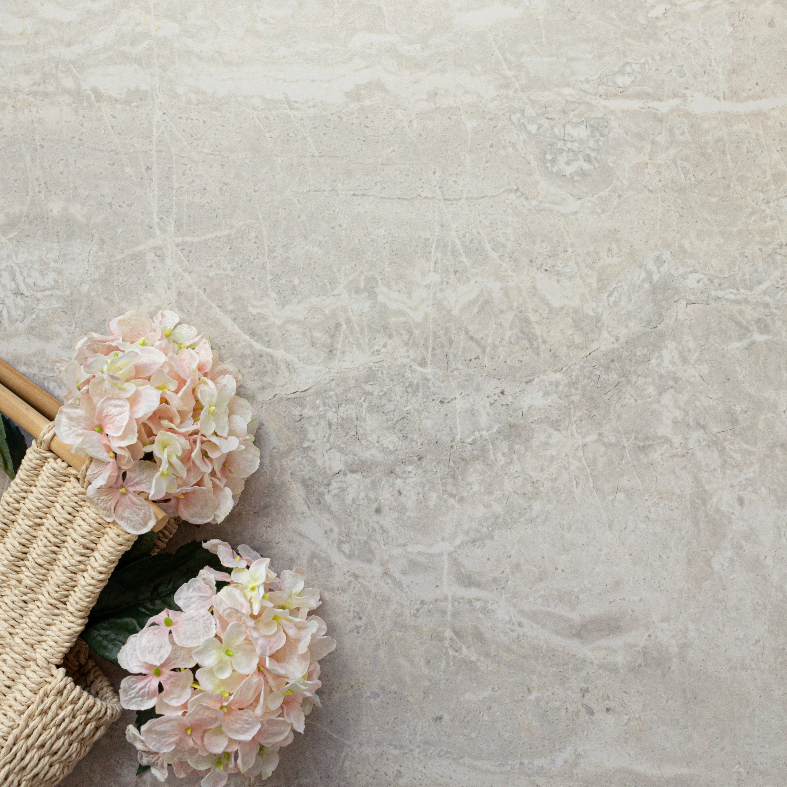 Soft ivory porcelain tile with natural marble-like veining and a woven basket holding pale pink flowers nearby