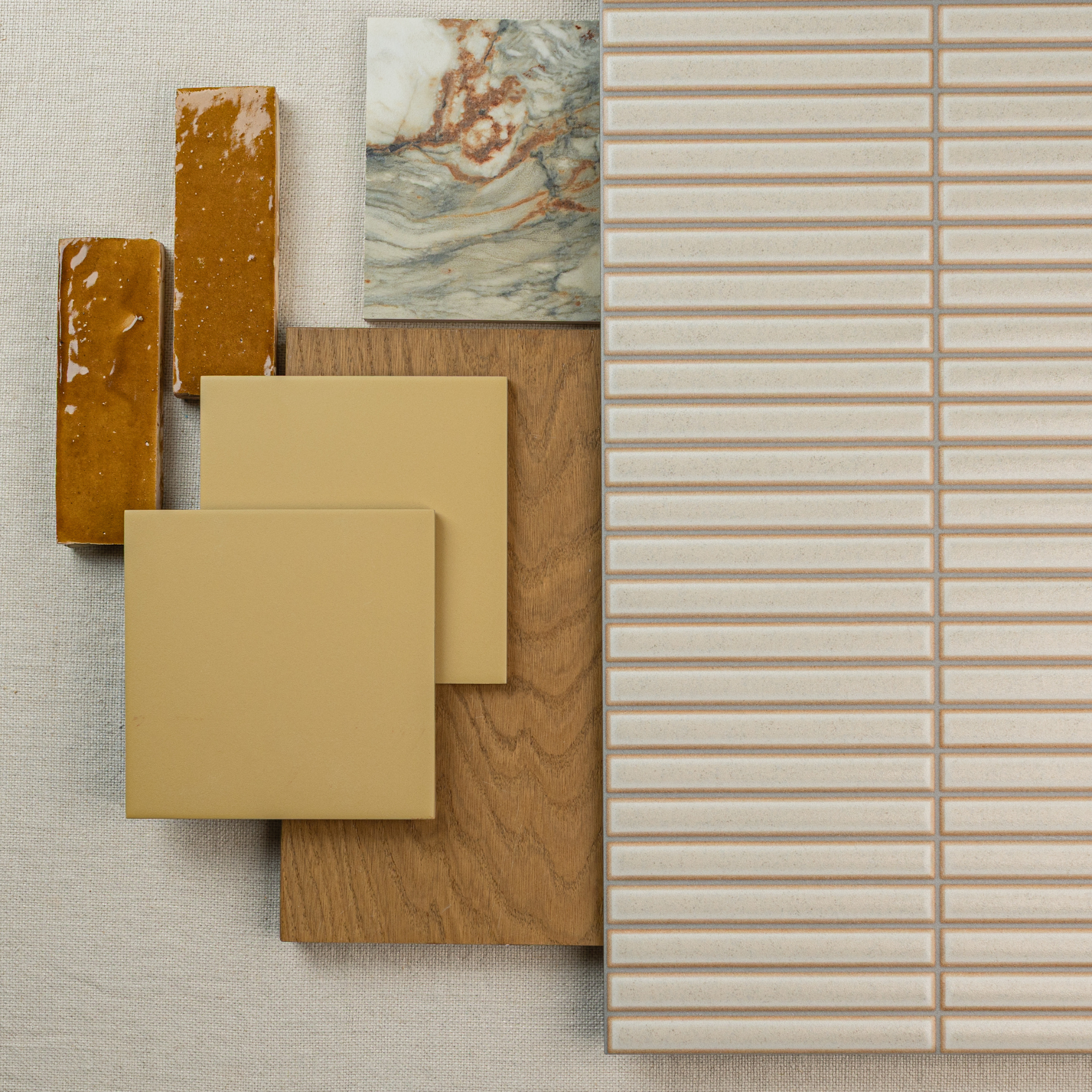 Assorted ceramic and porcelain tiles in cream and mustard tones arranged with wood and marble samples for design inspiration