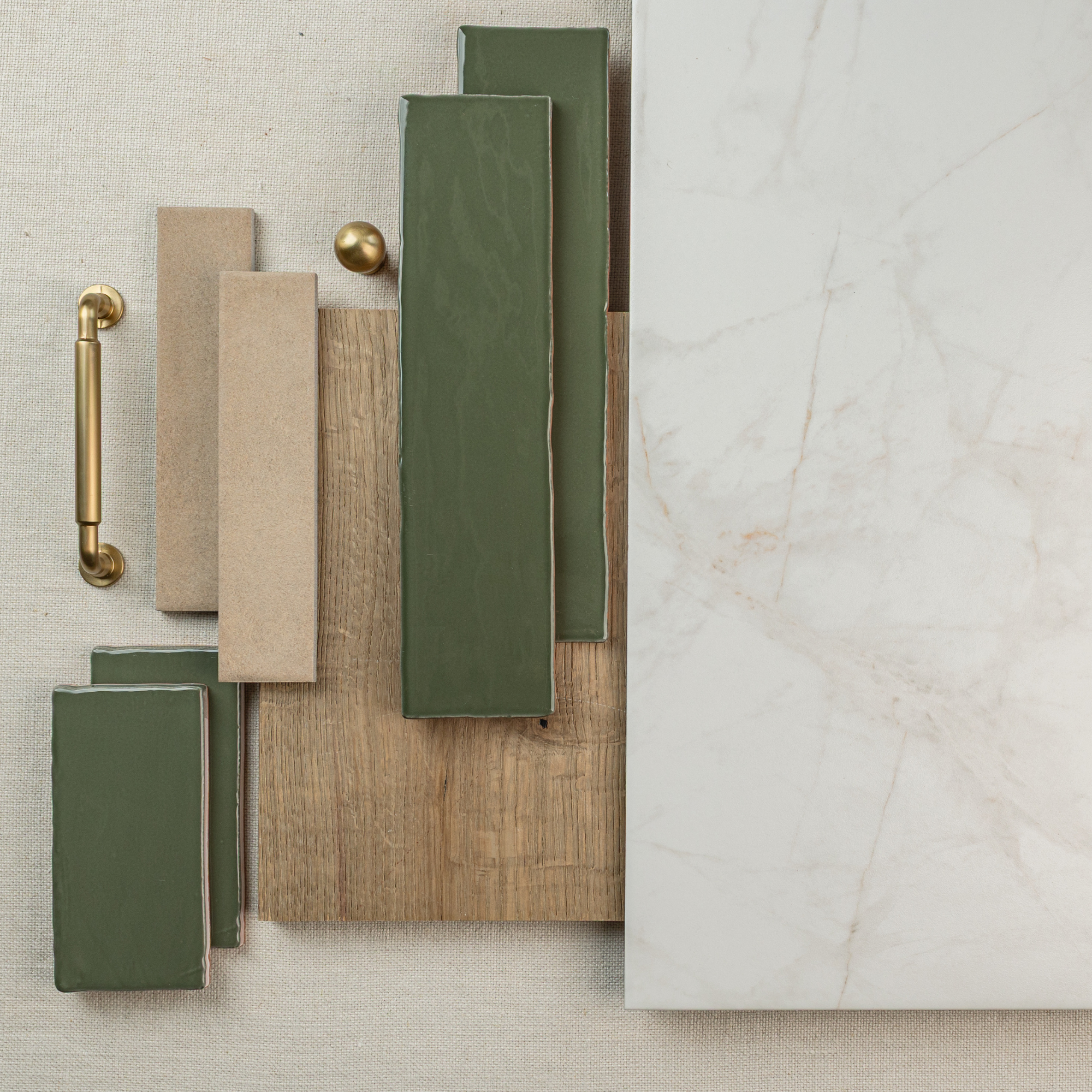 Flat lay of green ceramic tiles, beige samples, wood plank, brass hardware, and large white marble porcelain tile