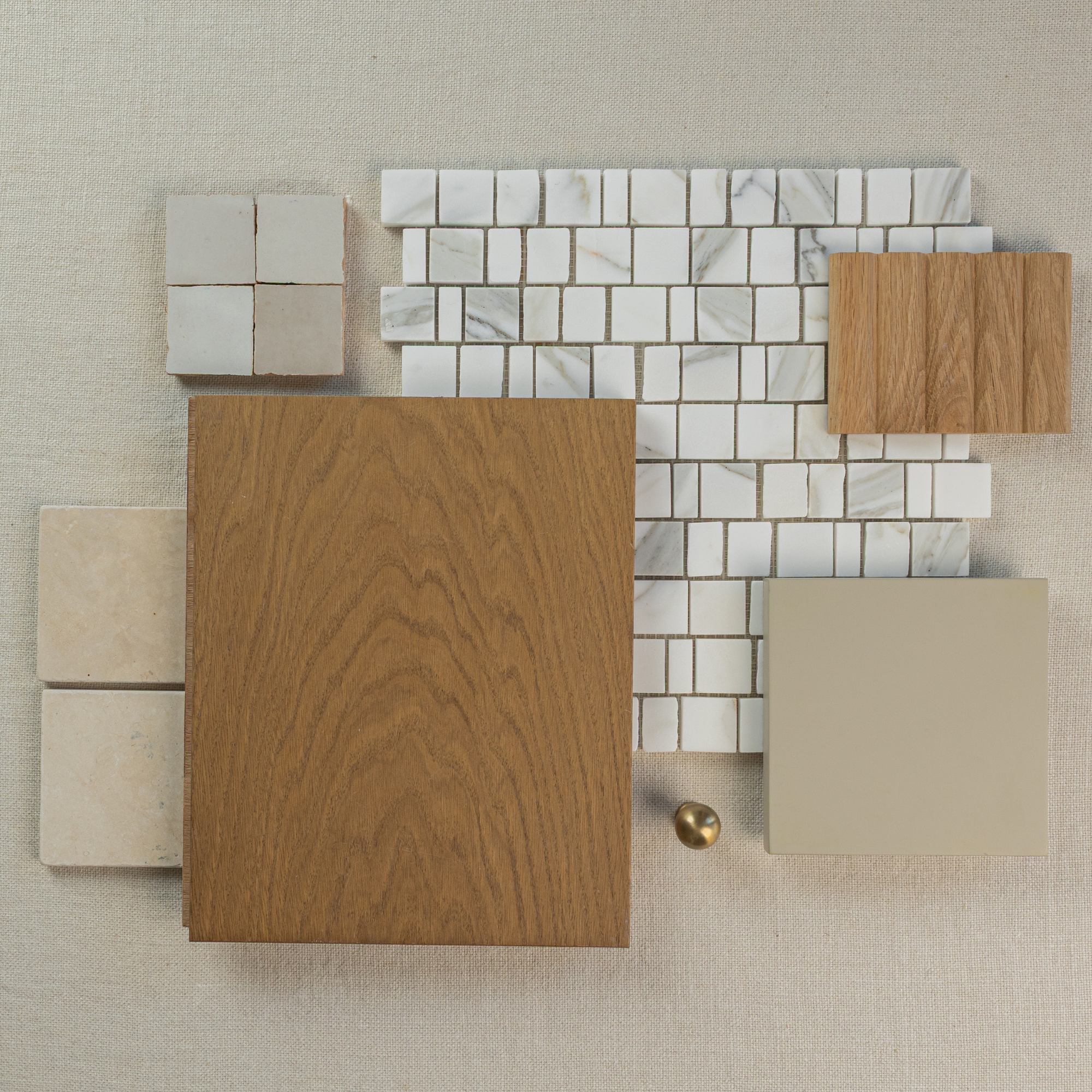 Top view of beige stone tiles, marble mosaic, wood planks, neutral ceramic tile, and brass hardware on light fabric background