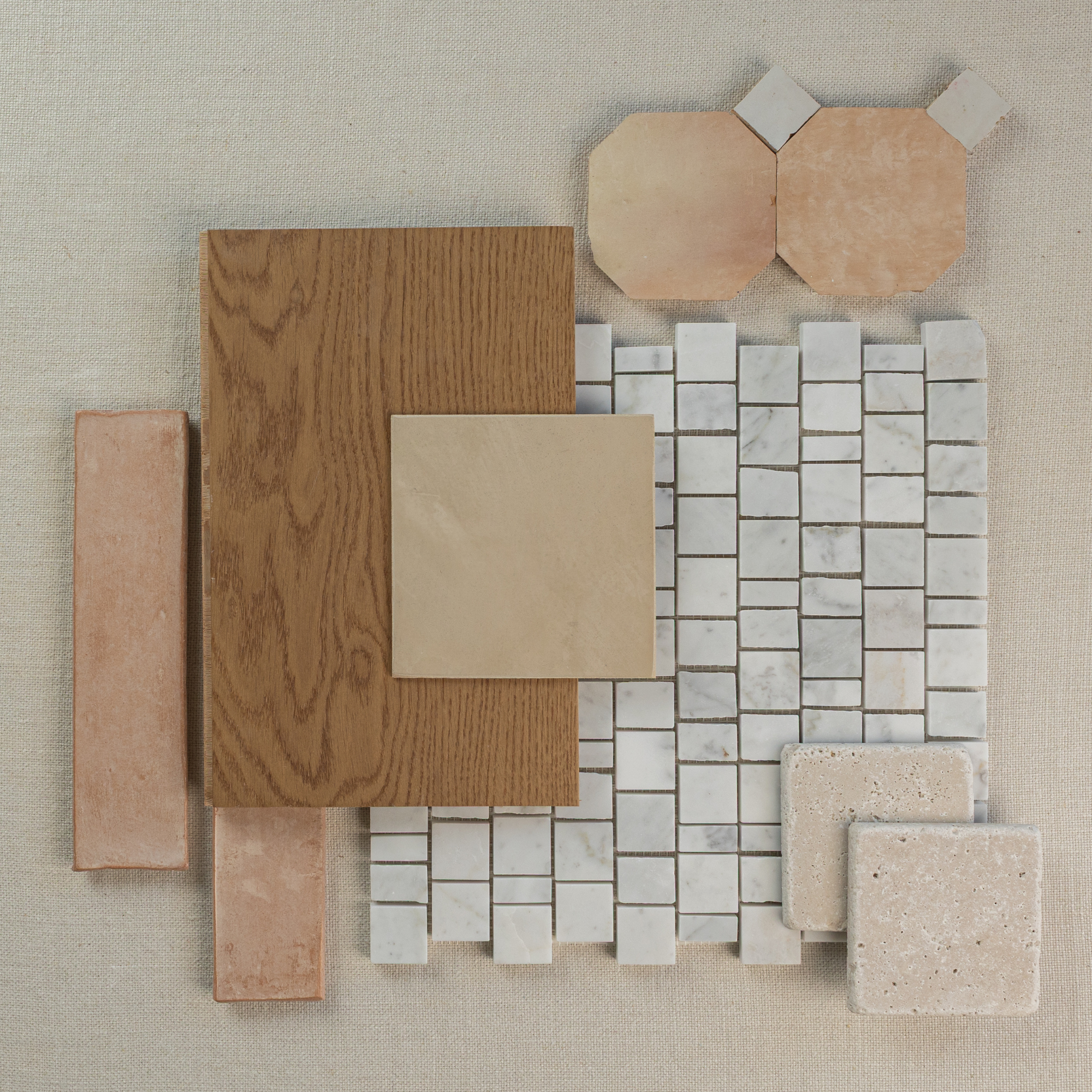 Flat lay of porcelain mosaic tile, oak wood plank, terracotta pieces, beige ceramic tile, and natural stone samples on fabric