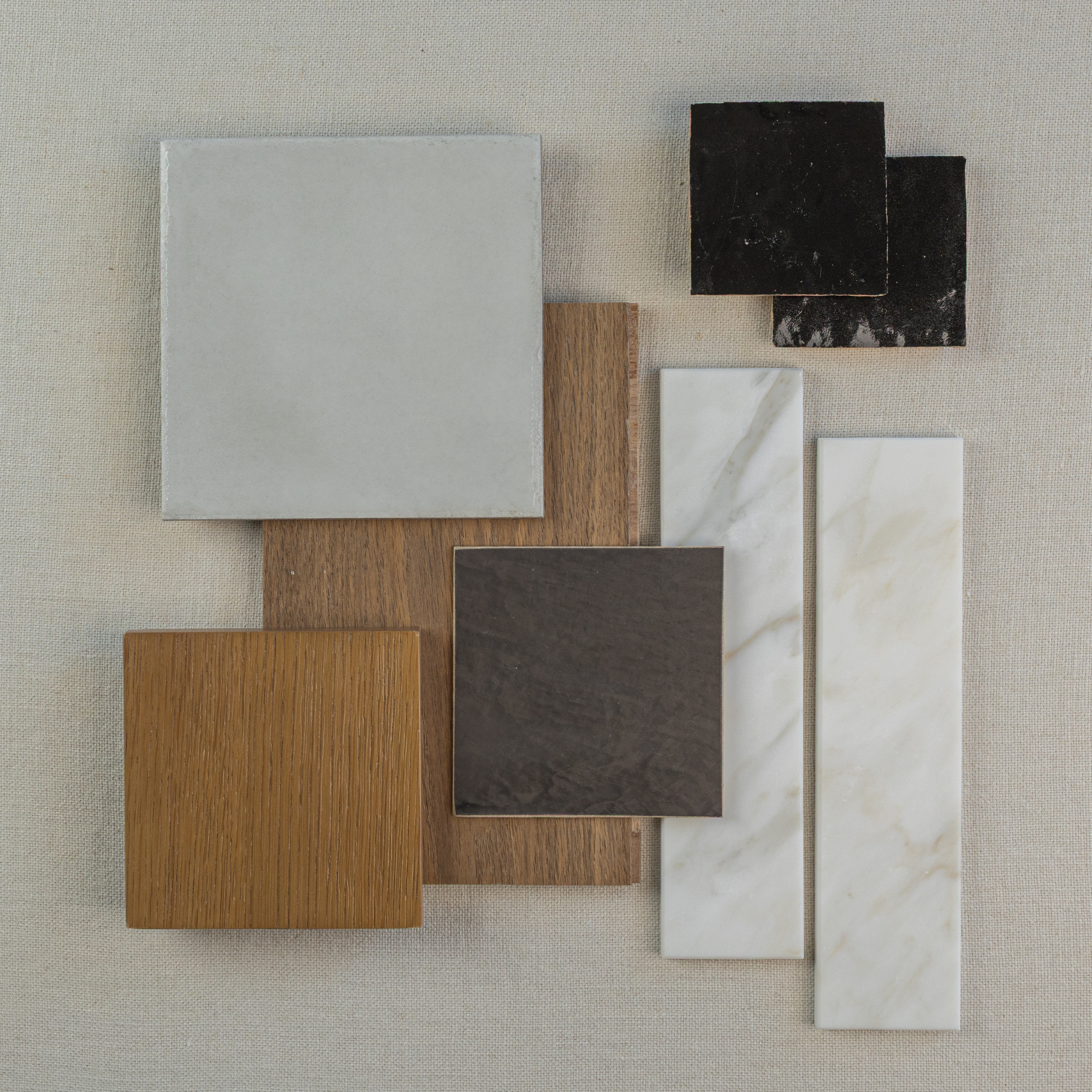 Collection of ceramic tiles and wood flooring samples in neutral shades, including beige, brown, black, and marble patterns.