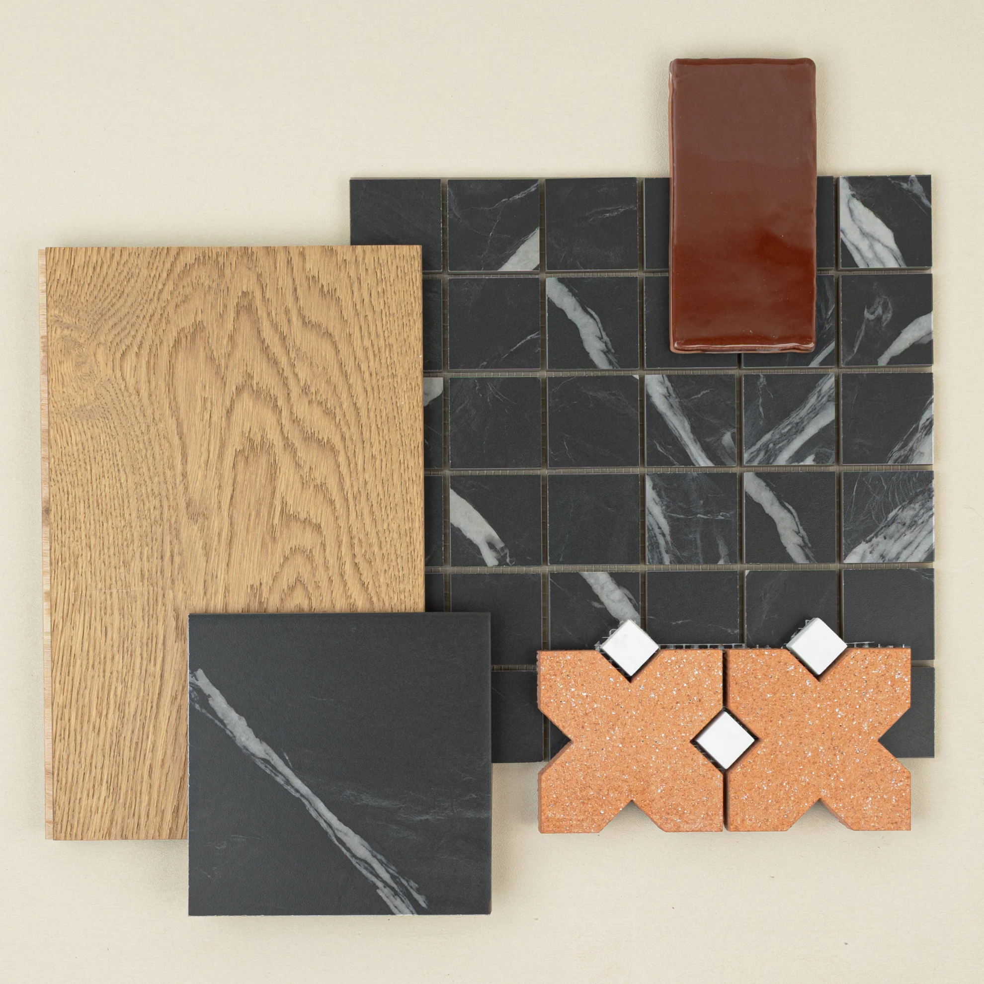 Assorted tile samples including black marble squares, textured terracotta shapes, wood plank, and glossy dark brown ceramic piece