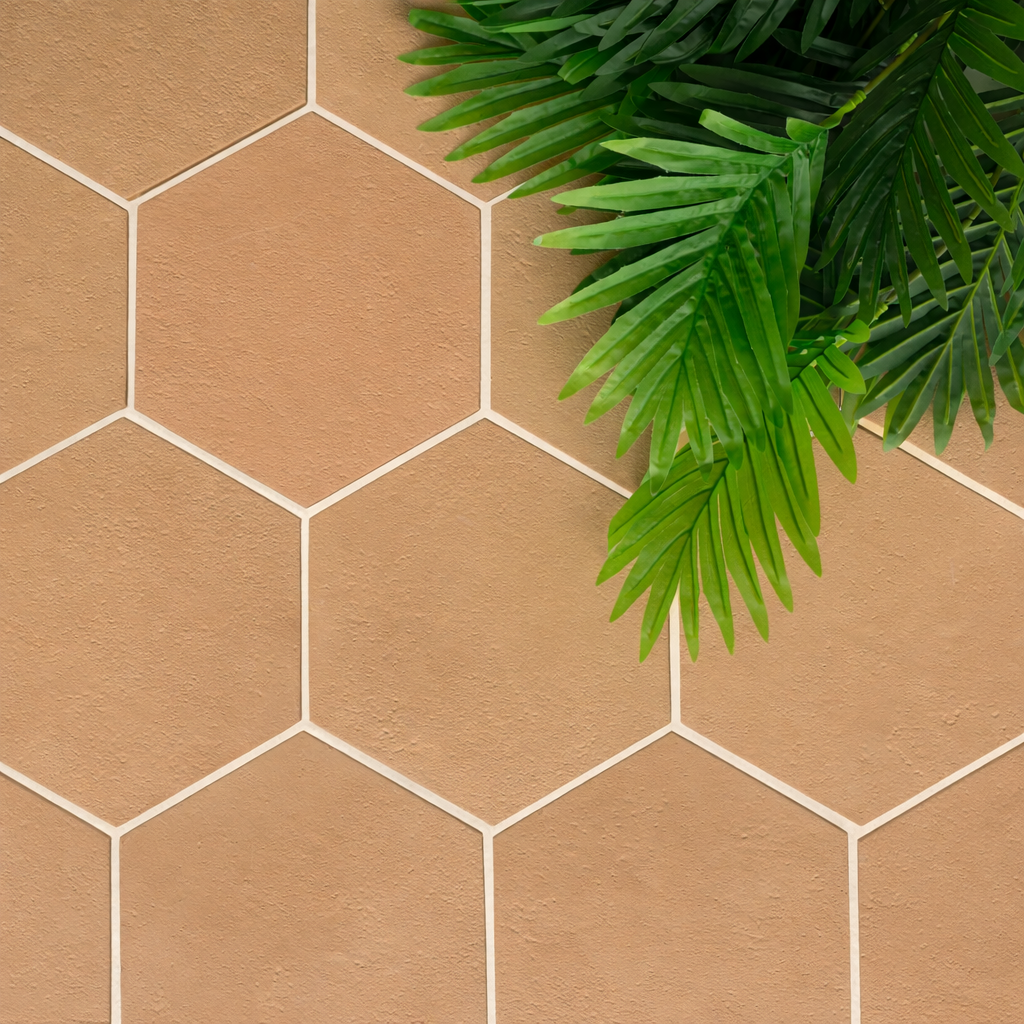 Hexagonal terracotta tiles with a natural matte finish complemented by green tropical plant leaves in the corner