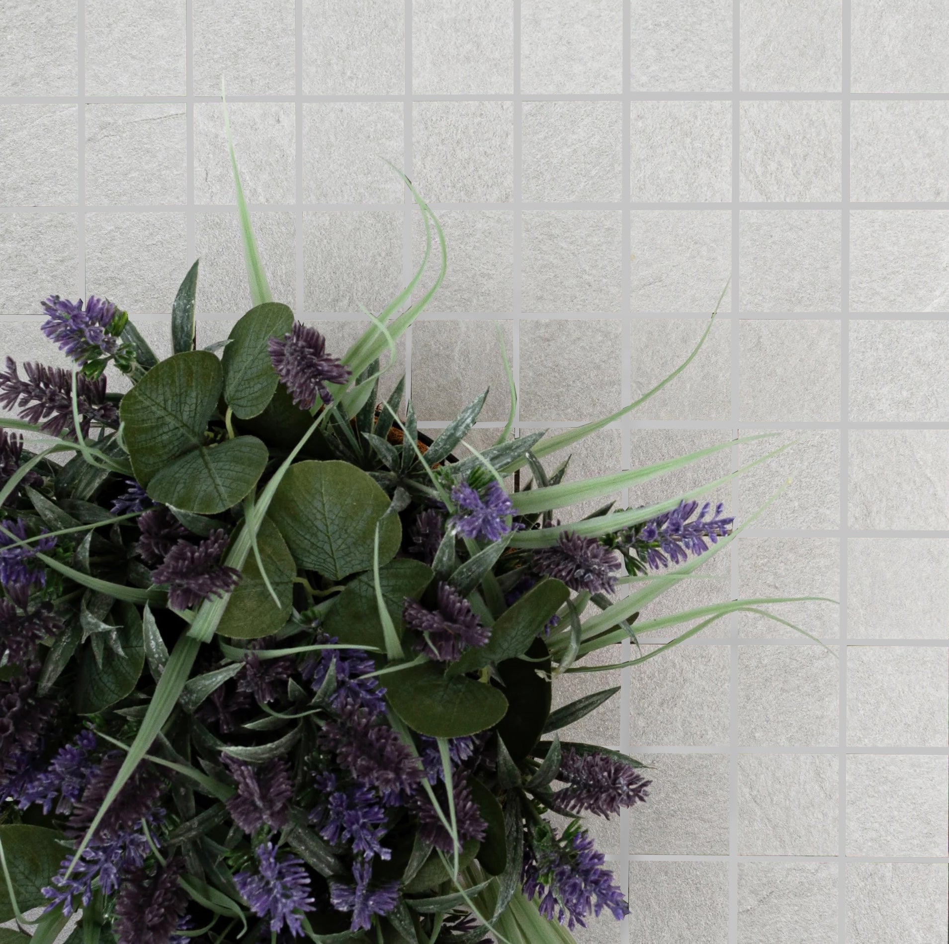 Square light gray ceramic tiles with subtle texture alongside green leaves and small purple flowers bouquet