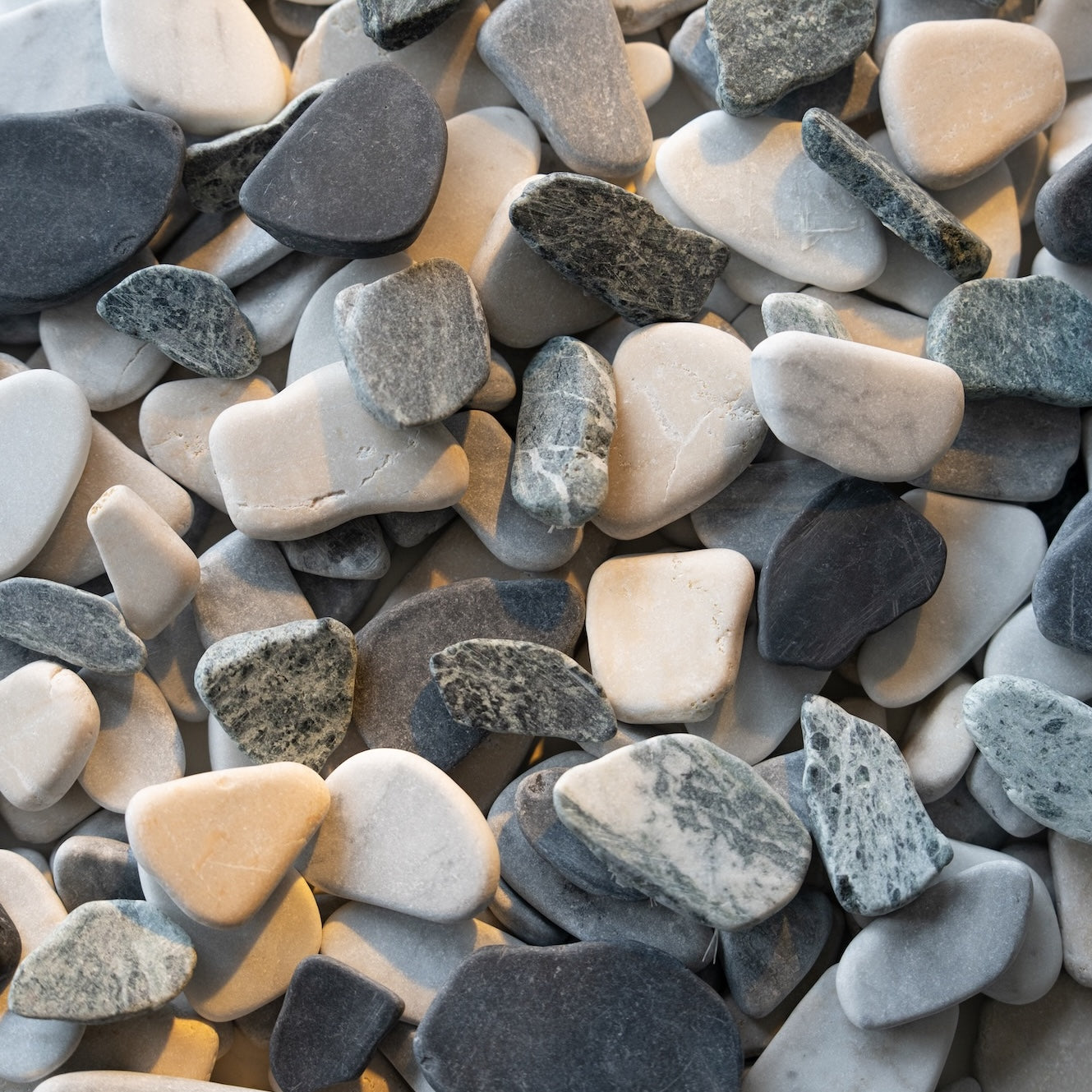 Close-up view of smooth gray, white, and black river pebbles with natural textures and varied shapes