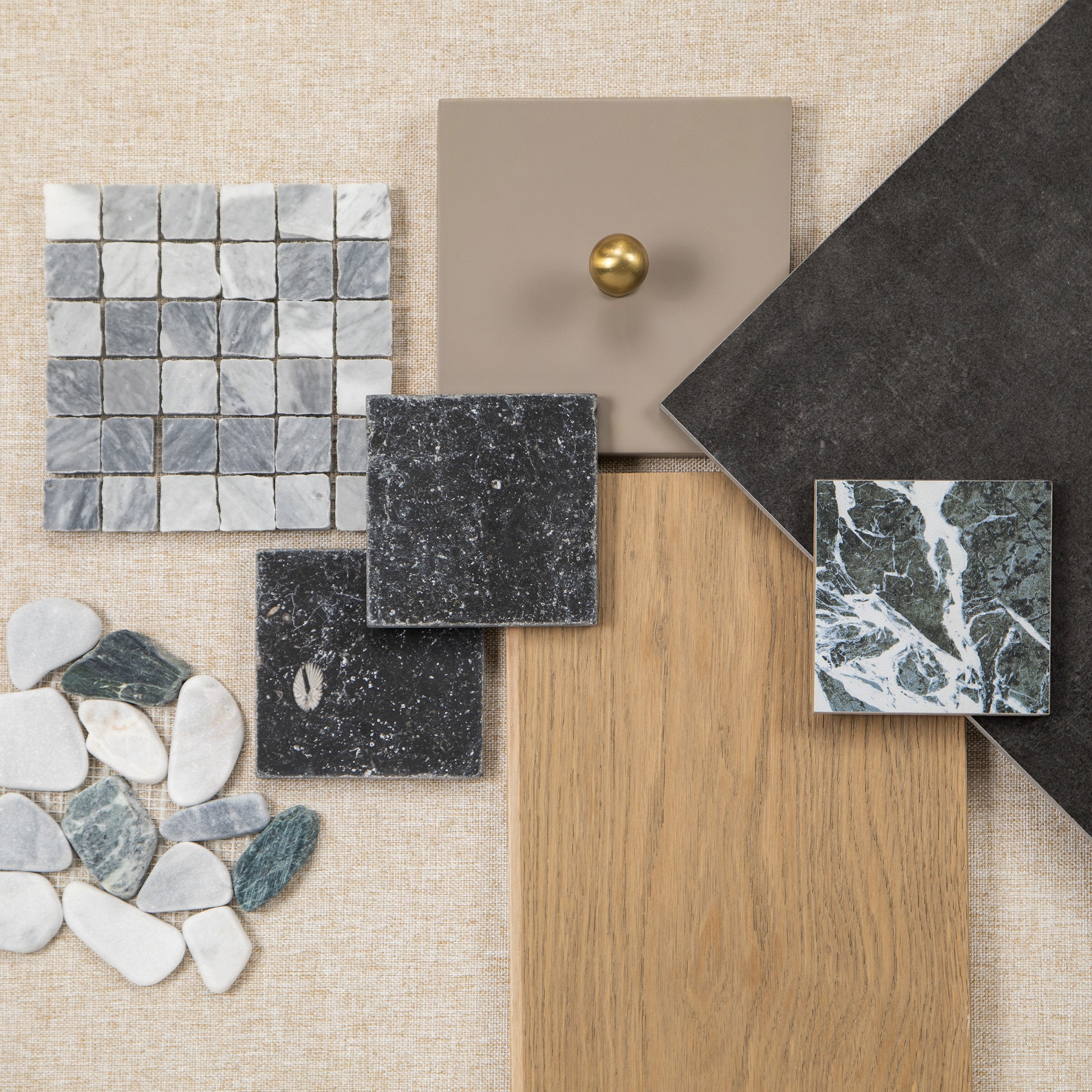 Interior materials mood board with mosaic tiles, wood flooring, stone samples, pebbles, and cabinet hardware