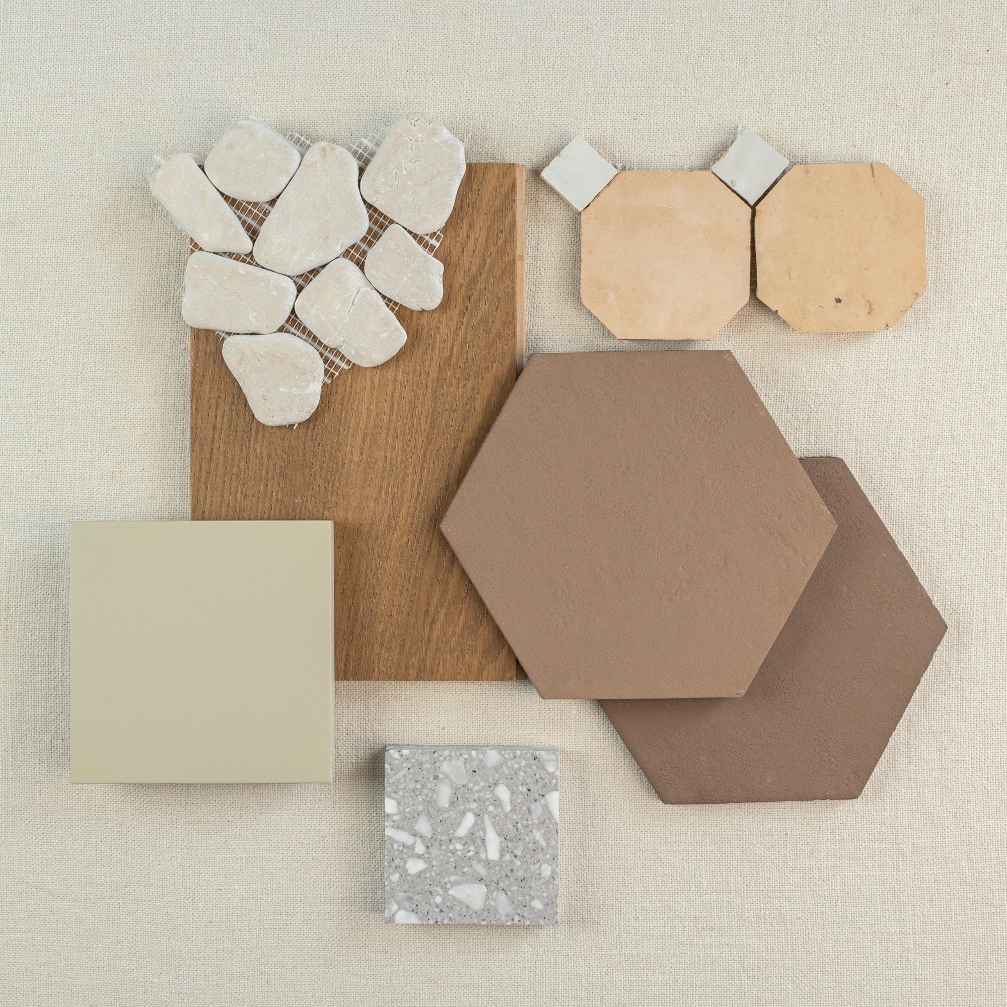 Assortment of beige, brown, and cream tiles and wood samples with varied shapes and textures on fabric surface