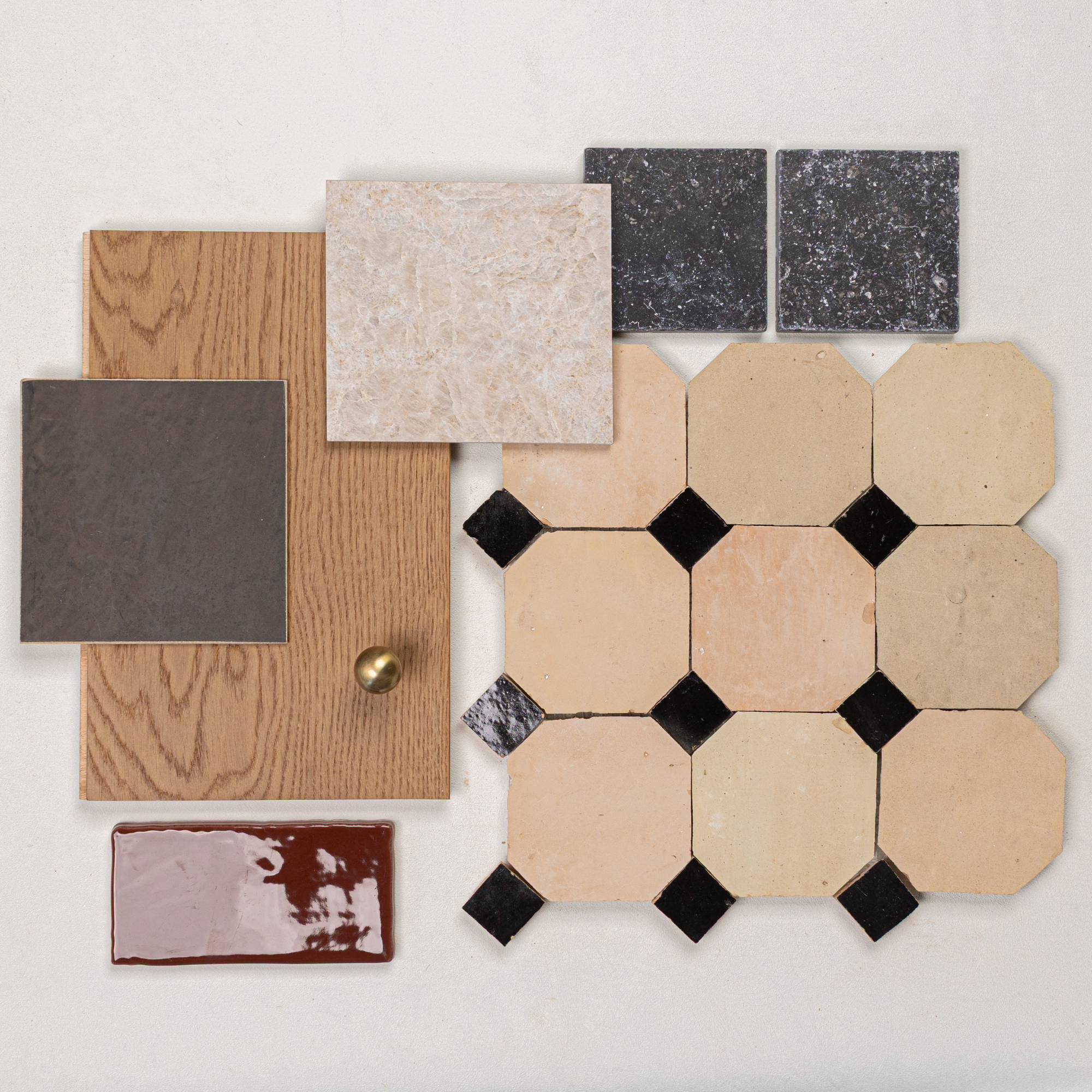 Assortment of beige octagonal tiles with black square accents, wood samples, dark square tiles, and glossy brown ceramic piece on white
