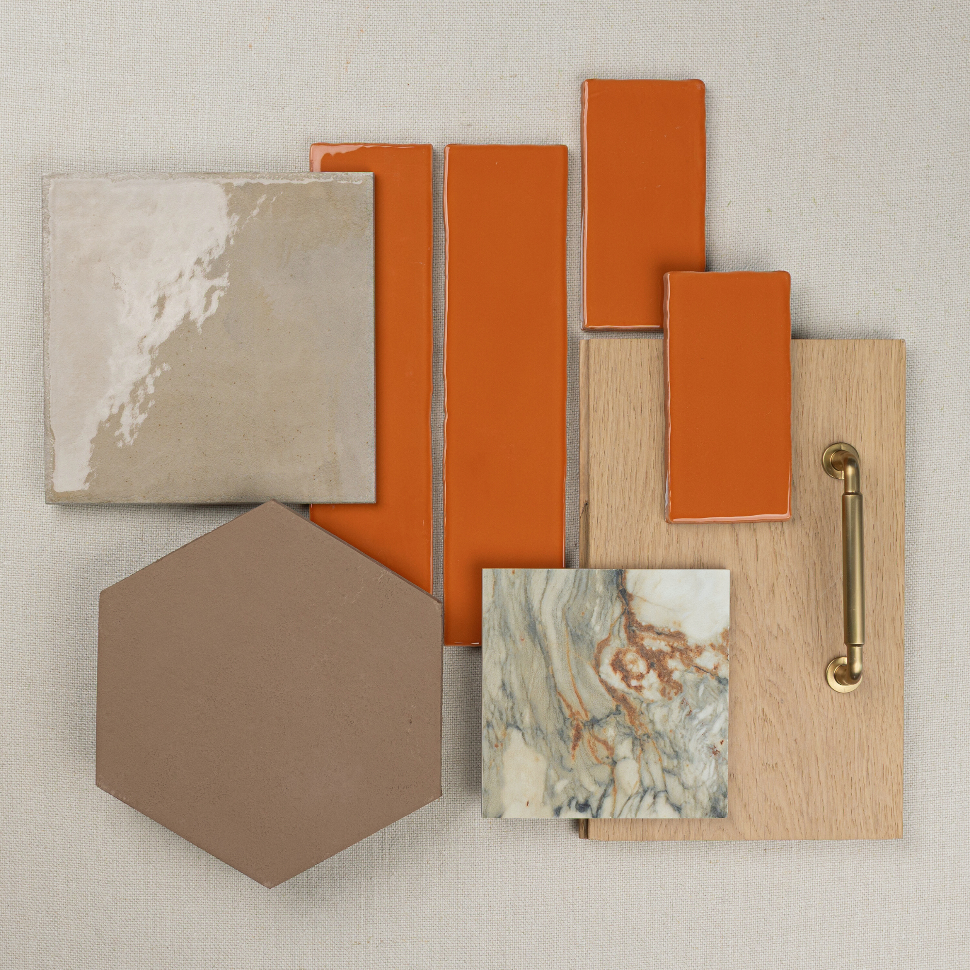 Glossy neutral and terracotta ceramic tiles, marble square, taupe hexagonal tile, oak sample with brass handle on fabric background