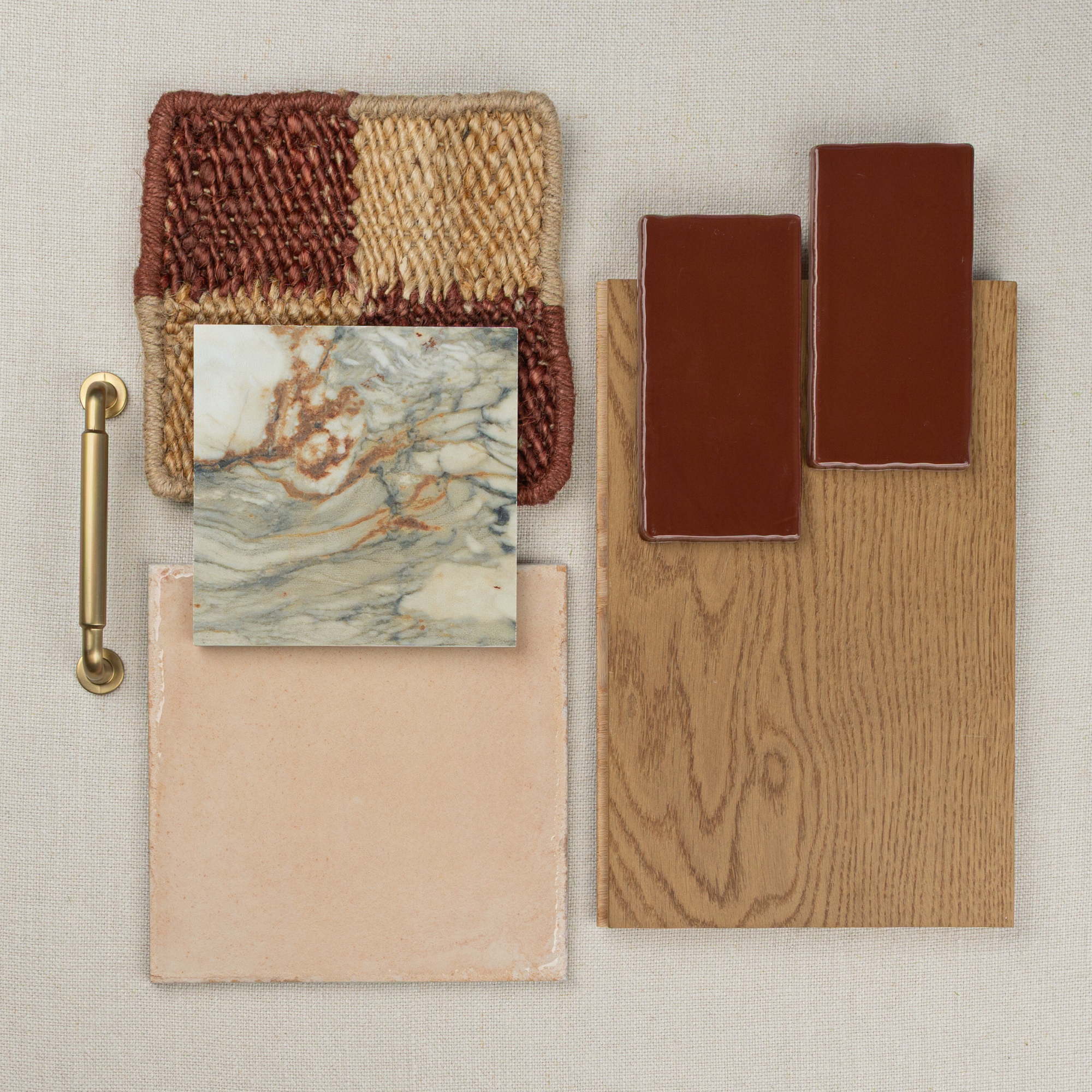 Flat lay of matte terracotta rectangular tiles, oak wood plank, marble tile, beige square tile, textured woven fabric, and brass pull handle on neutral fabric