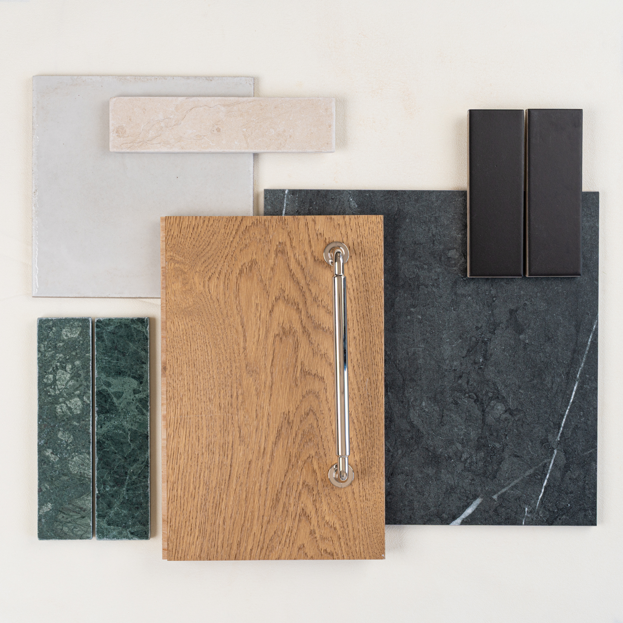 Flat lay of various flooring and tile samples including oak wood, black marble, green stone, beige ceramic, and matte black tiles