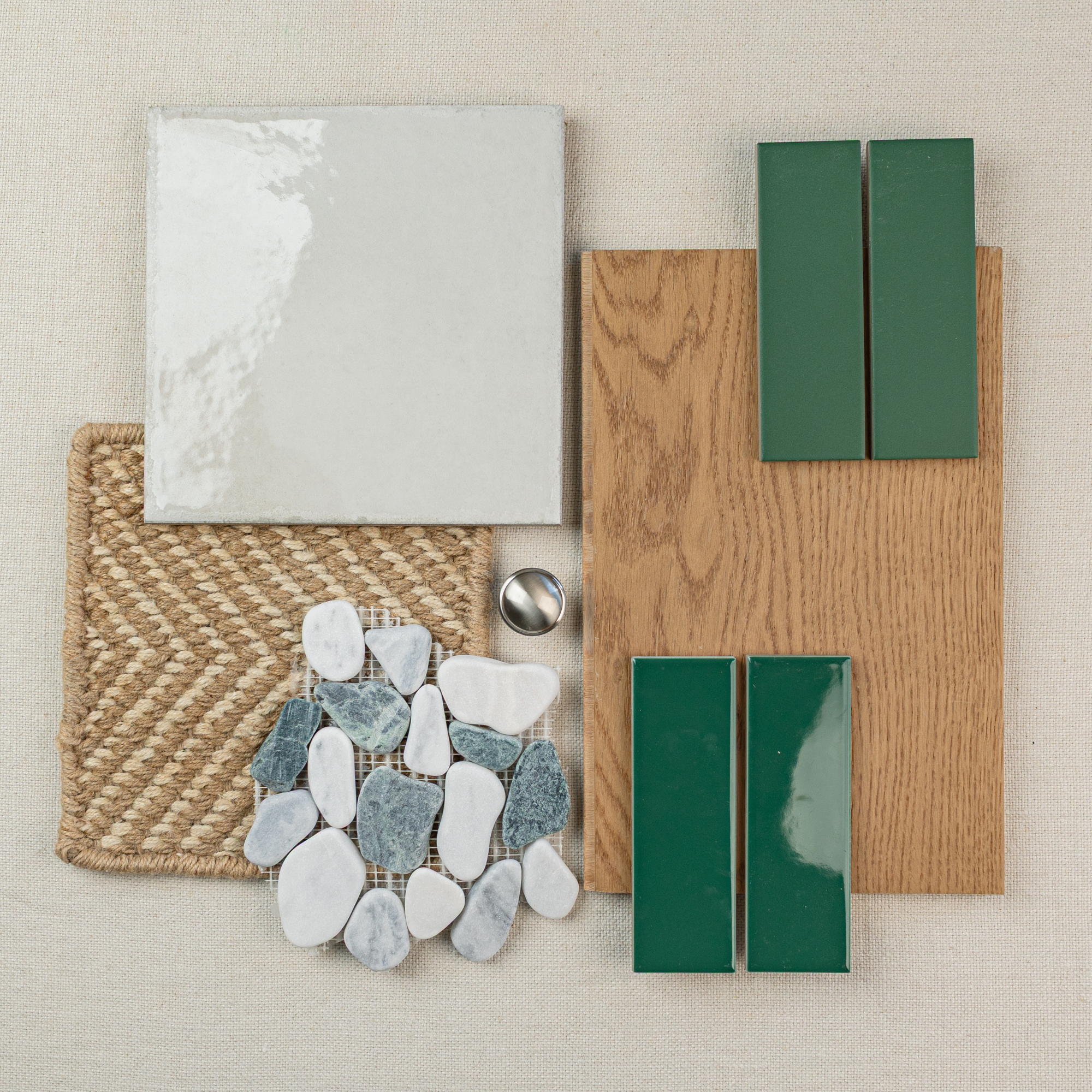 Neutral tile, natural woven fabric, wood plank sample, green ceramic tiles, and mixed stone mosaic pieces arranged on beige background
