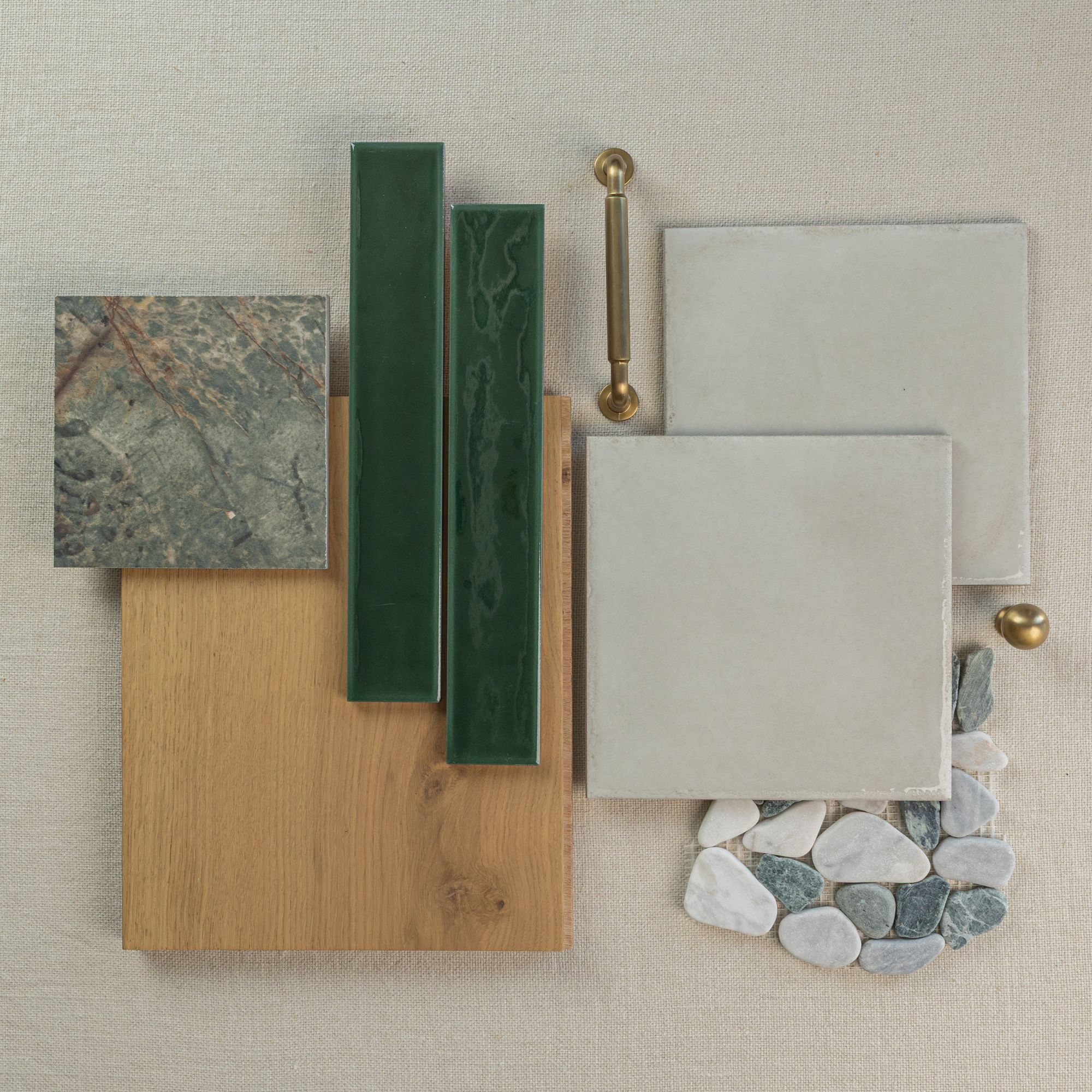 Flat lay of natural oak wood, green ceramic tiles, smooth porcelain tiles, stone mosaic pieces, and brass hardware on neutral background