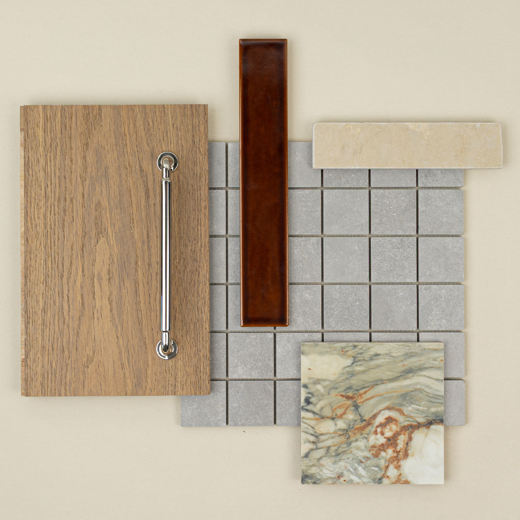 Flat lay of oak wood sample with metal handle, grey square mosaic tile, beige ceramic tile, brown rectangular tile, and marble stone sample