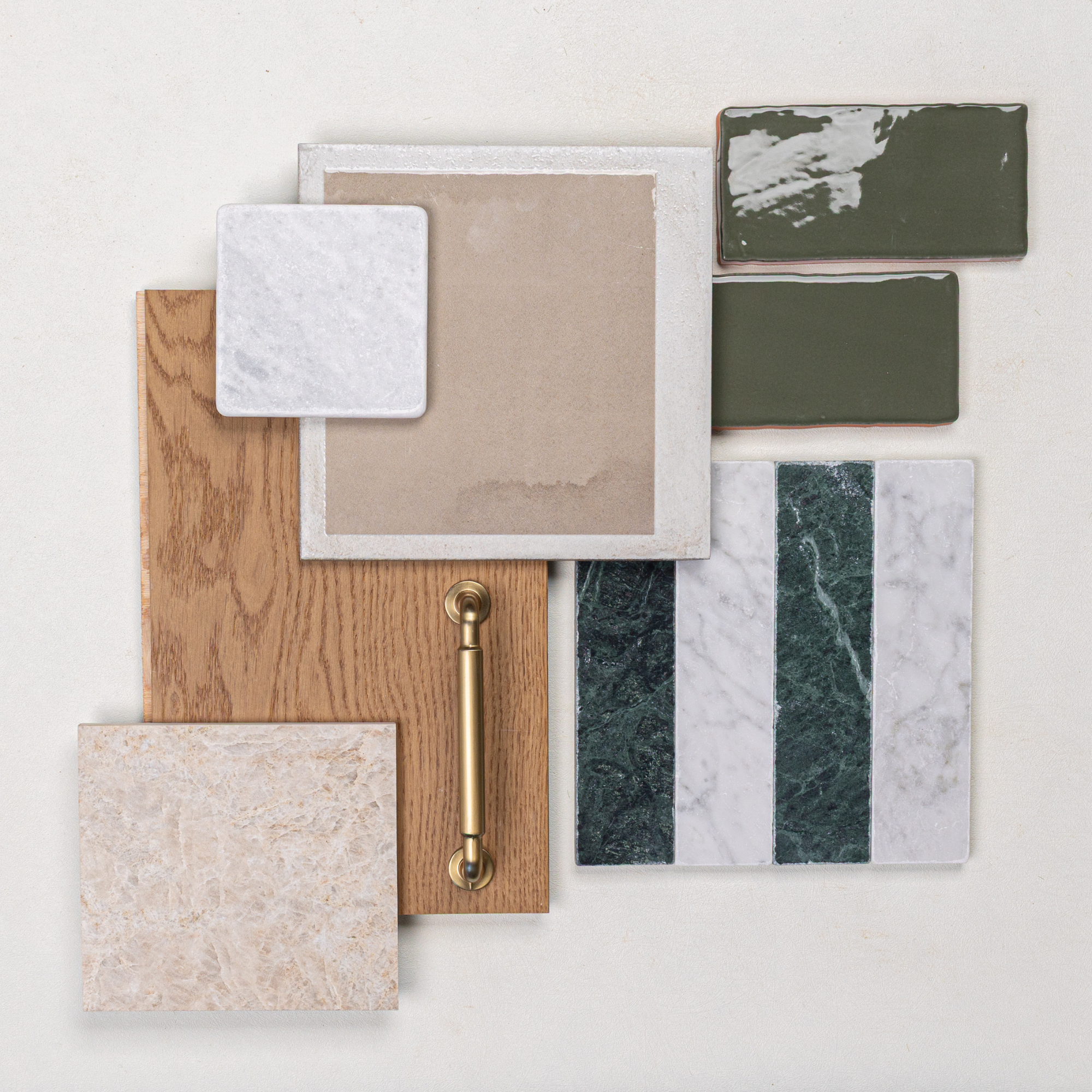 Flat lay of oak wood sample with brass handle, beige and white ceramic tiles, green glazed tiles, and striped marble tile pieces
