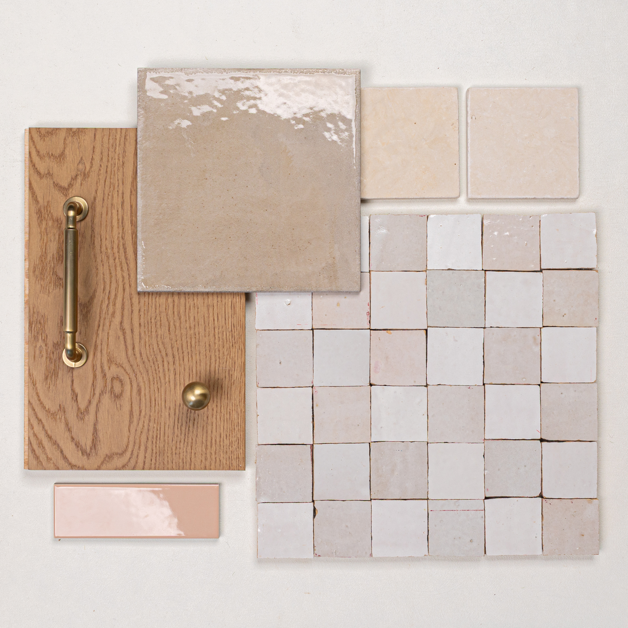Arrangement of light beige ceramic tiles, small square mosaic tiles, oak wood panel with brass hardware, and glossy accent tile on white background