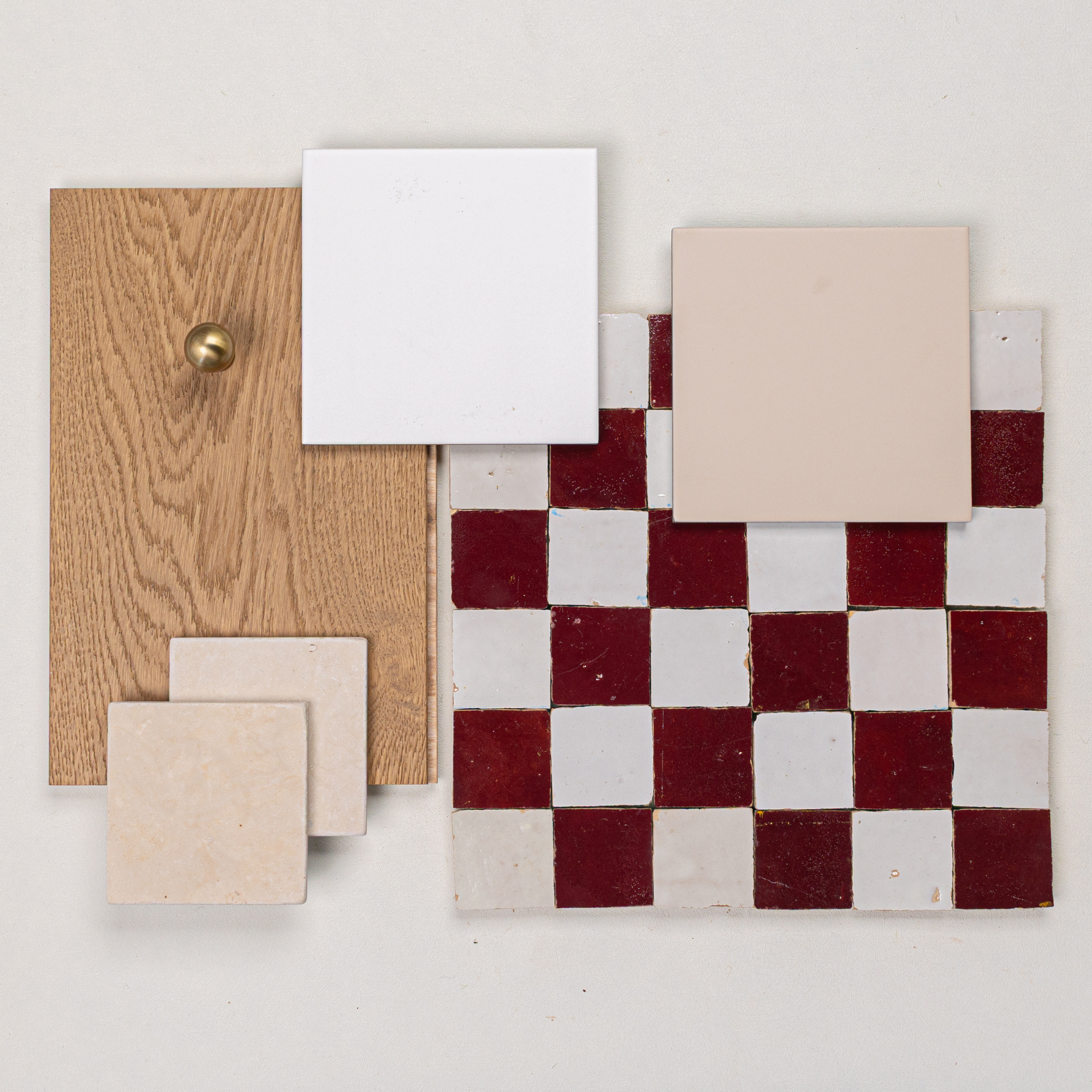 Flat lay of oak wood panel with brass knob, beige and white ceramic tiles, and red and white checkerboard tile piece