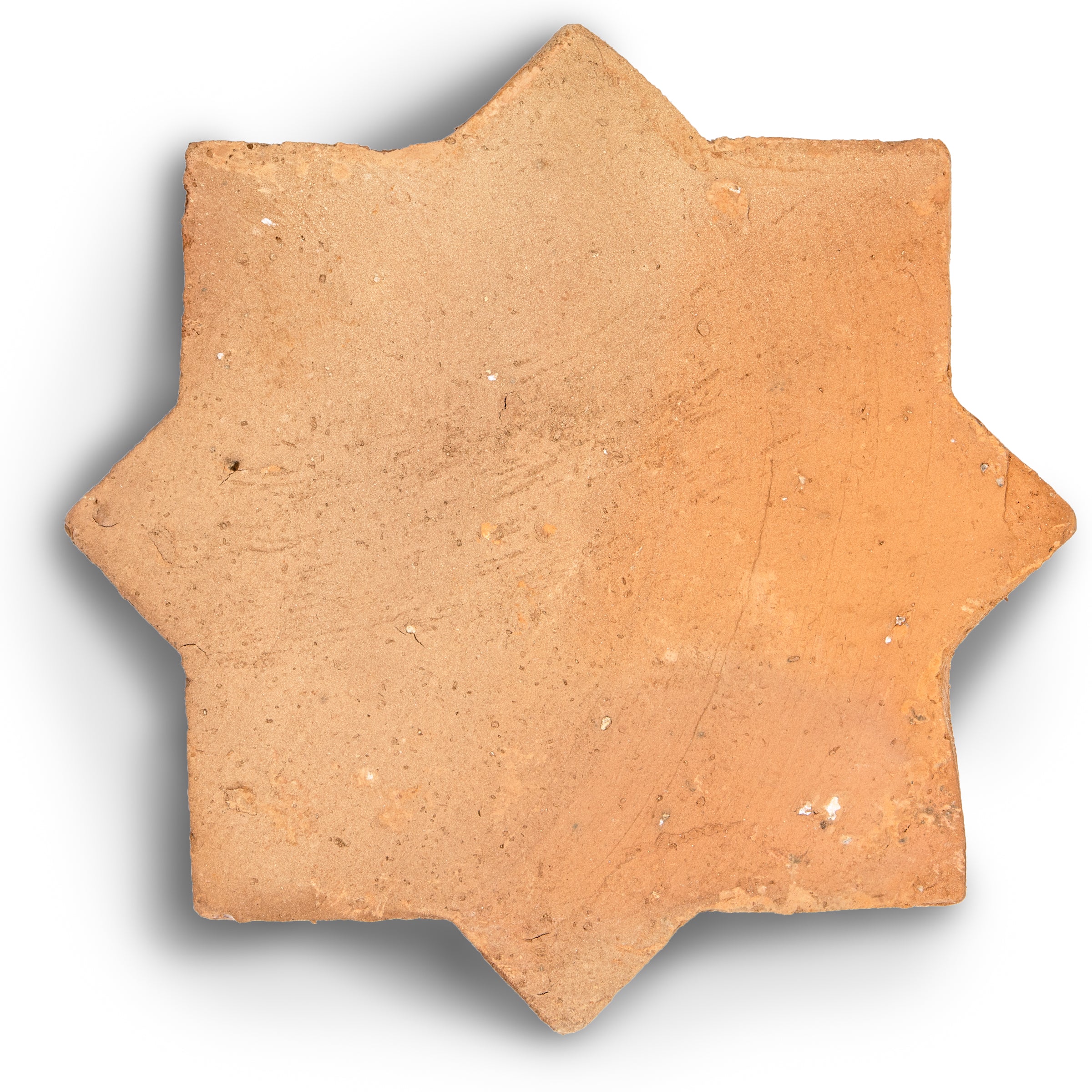Terracotta tile with star-shaped edges in warm clay tones showcasing natural texture and handcrafted finish