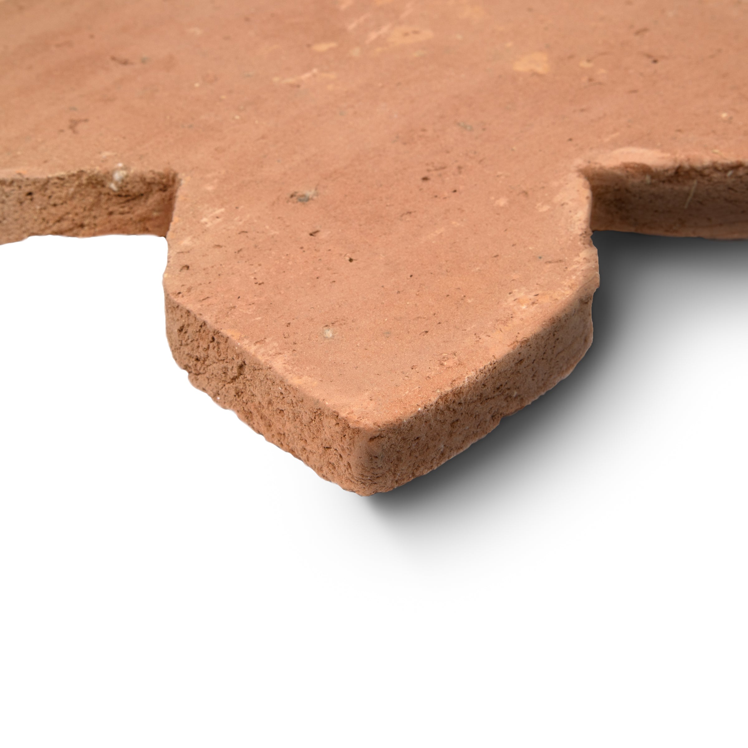 Close-up of terracotta tile corner with natural rough texture and warm earthy tones on white background